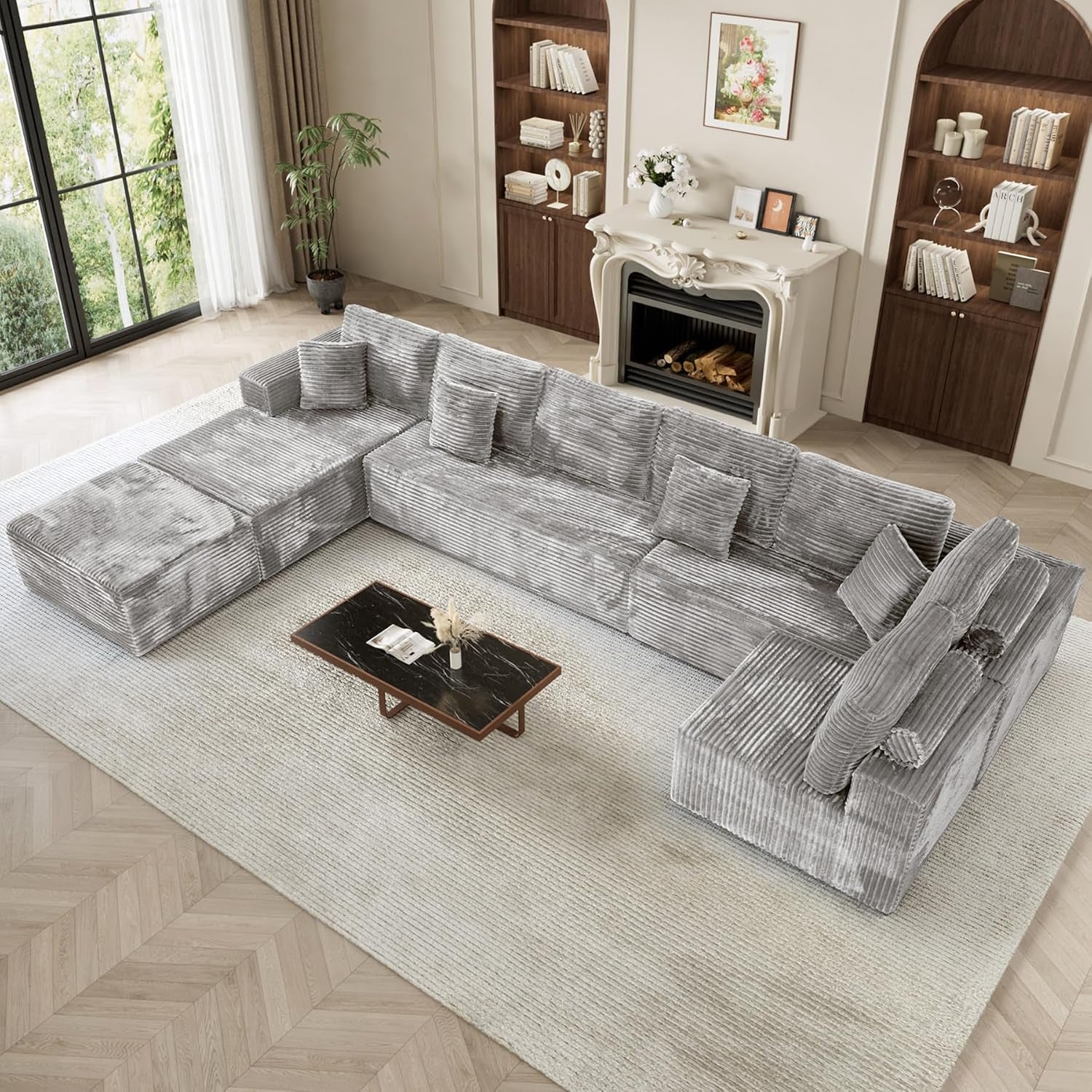 A large L-shaped sectional with chaise in light gray corduroy fabric placed on a pale rug in a bright living room.