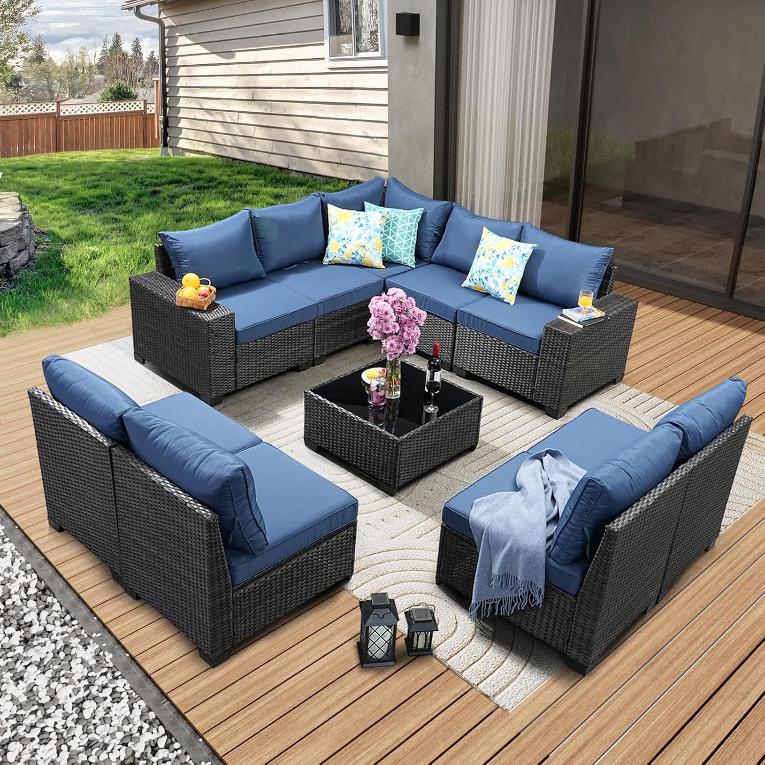 Same patio set with dark rattan and deep blue cushions arranged in a U-shape around a black glass coffee table.