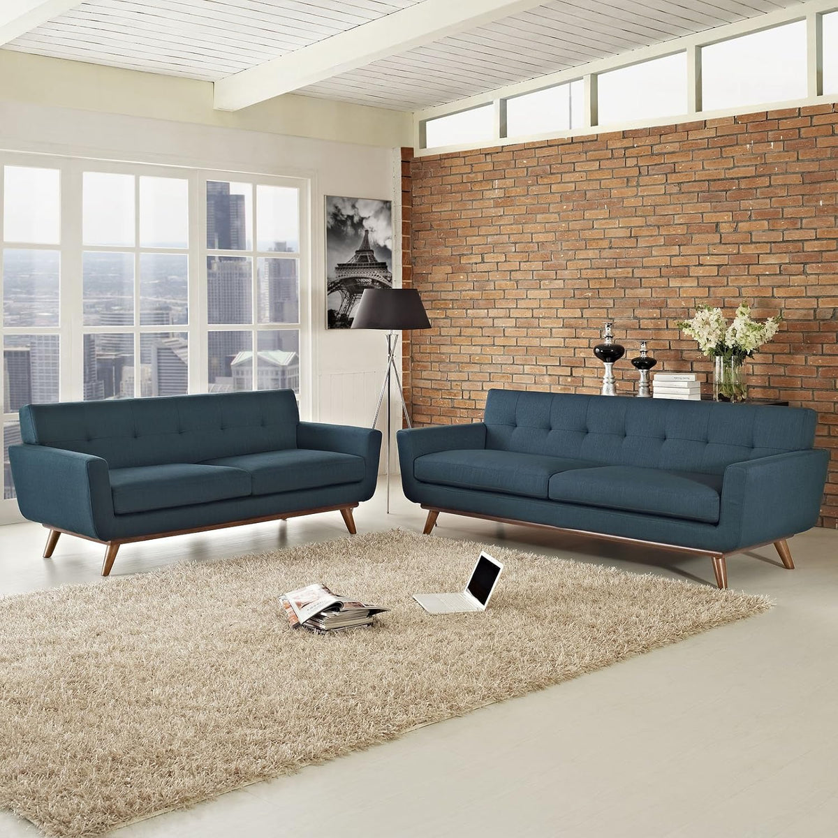 Azure sofa and loveseat staged in a living room with brick accent wall and shag rug