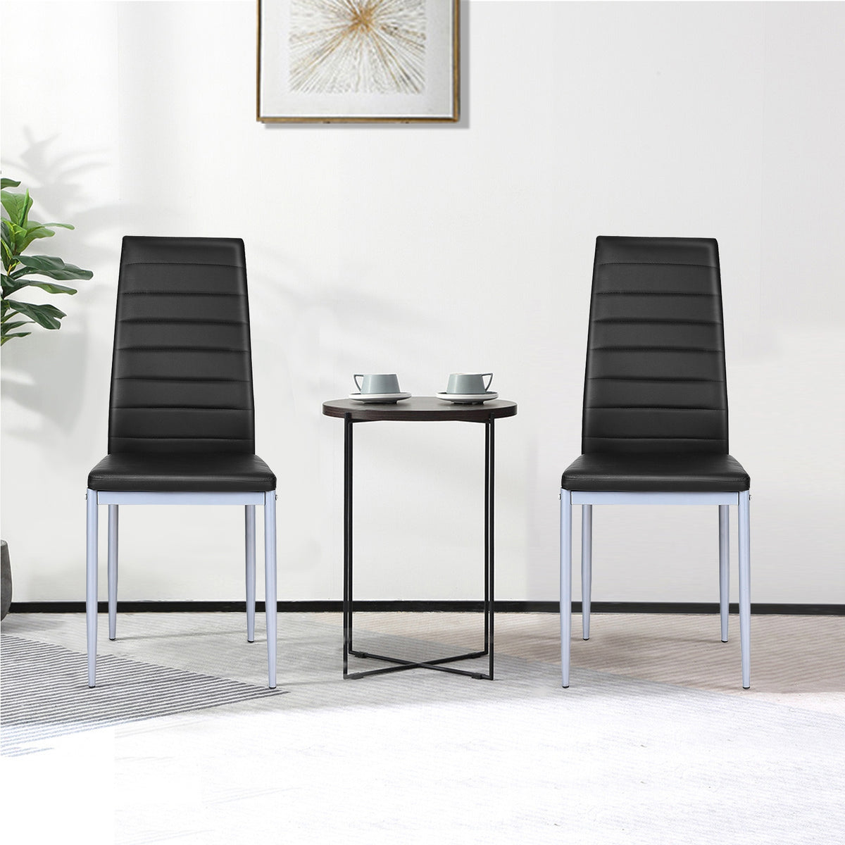 Two black dining chairs beside a small table with cups in a bright room.