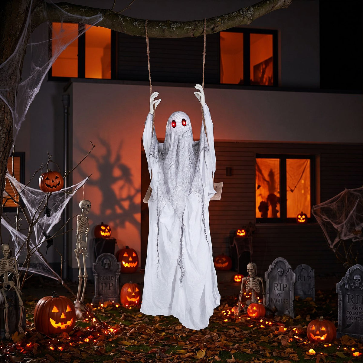 White red-eyed ghost hanging over a porch decorated with Halloween lights and pumpkins