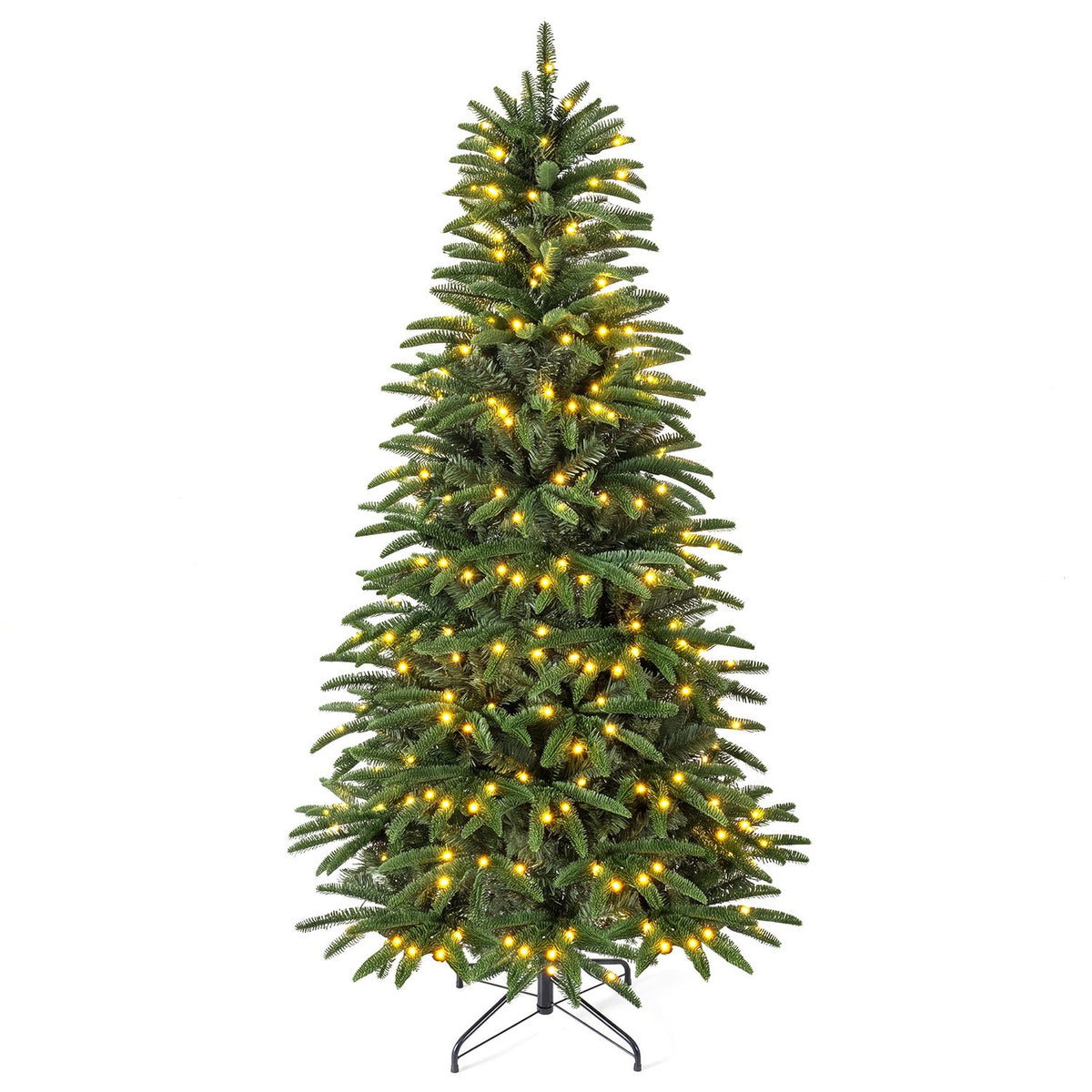 Warm-lit green artificial Christmas tree standing against a white background