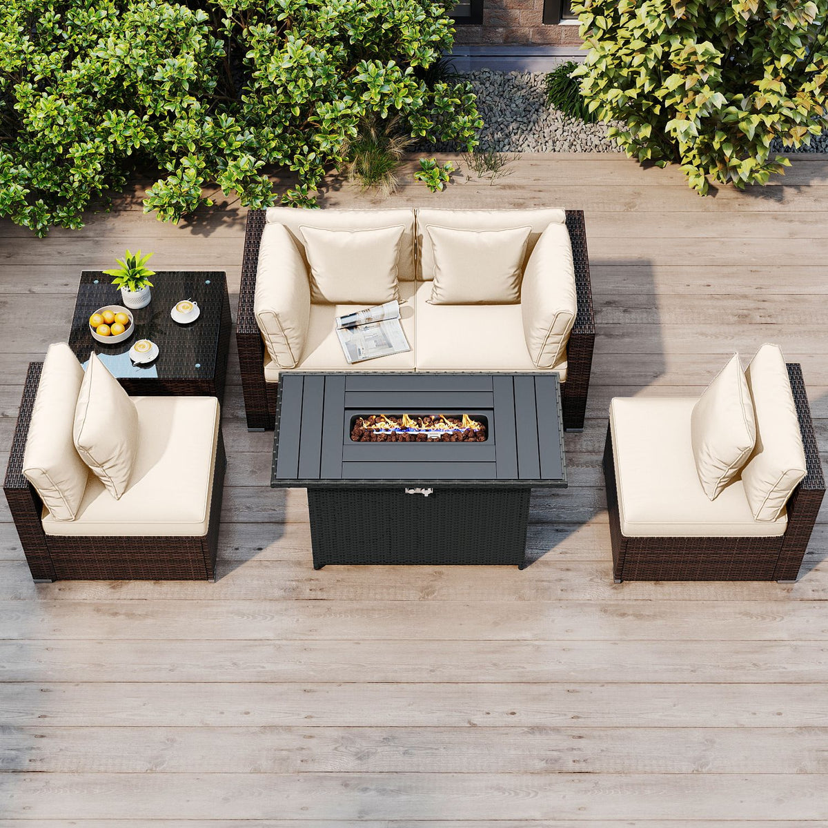 Overhead view of a patio conversation set with cream cushions, dark woven frames, and a lit fire pit table.