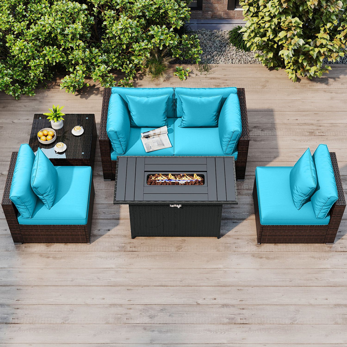 Overhead view of turquoise cushioned patio seating around a rectangular fire pit table on a wooden deck.