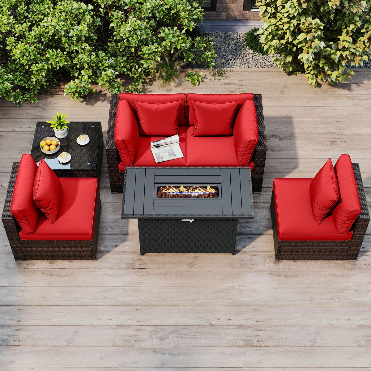 Overhead view of a patio conversation set with red cushions, dark woven frames, and a lit fire pit table.
