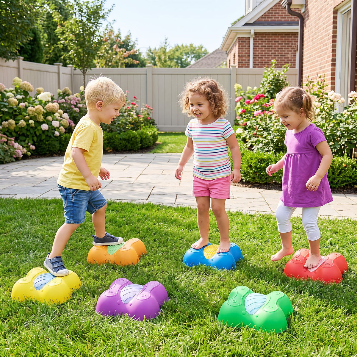 Three children balance on colorful butterfly-shaped stepping stones across a grassy yard.