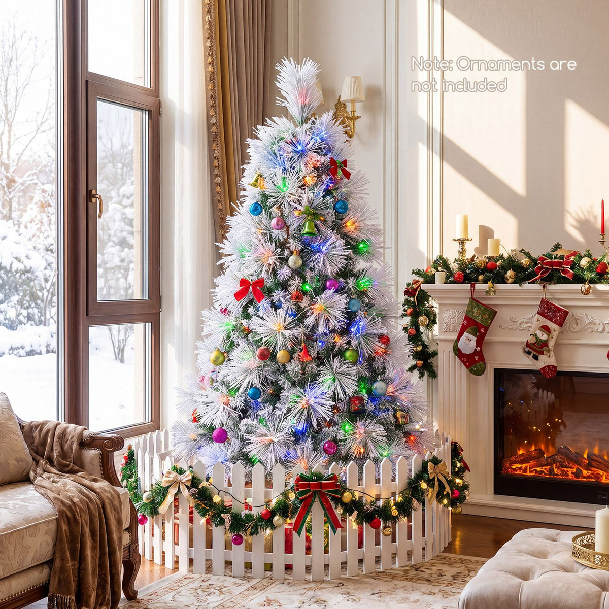 Colorfully lit frosted tree decorated with ornaments inside a white picket fence beside a fireplace.
