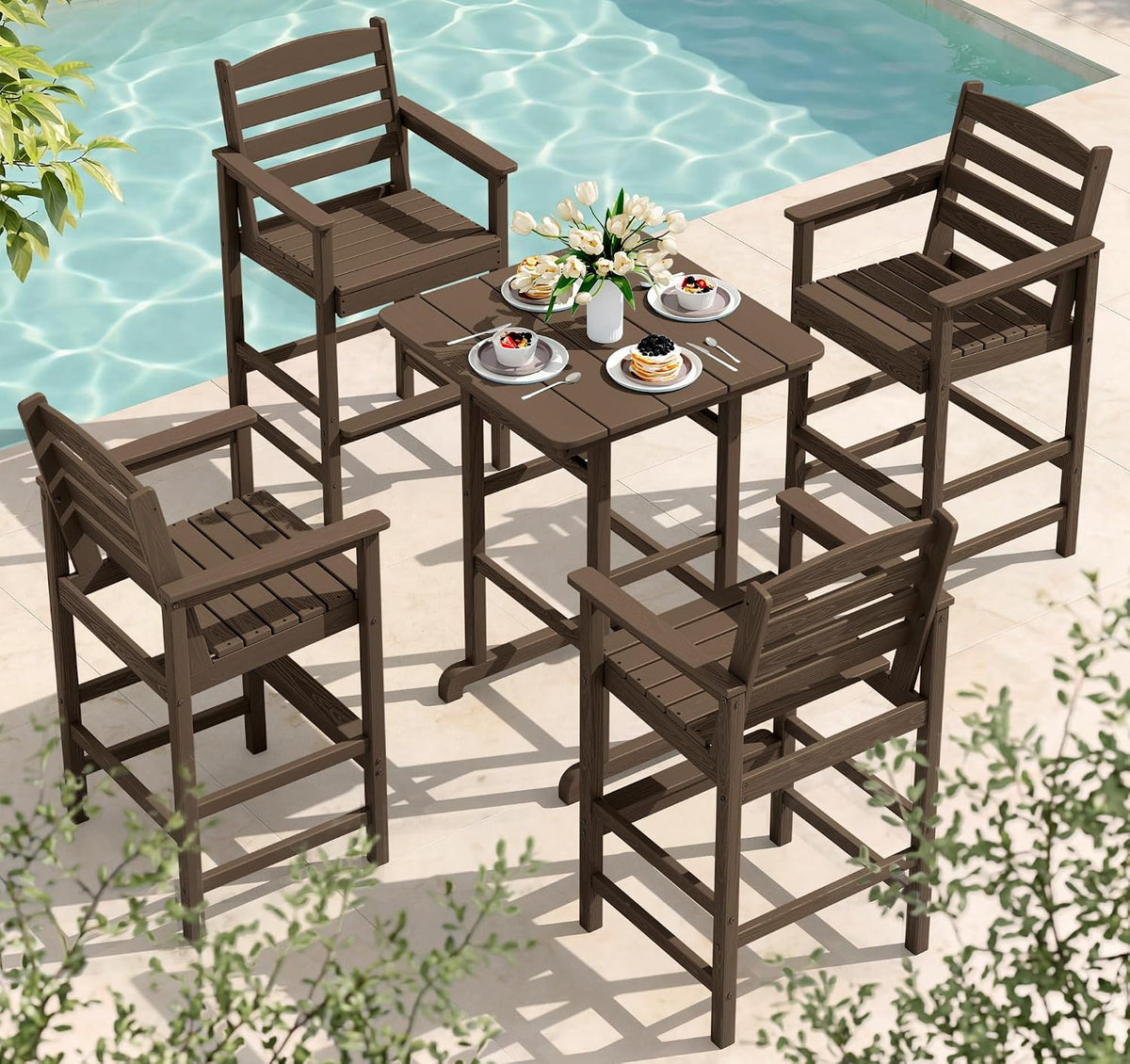 Brown five-piece arrangement with four bar chairs around a square table set by a pool with plates and flowers.