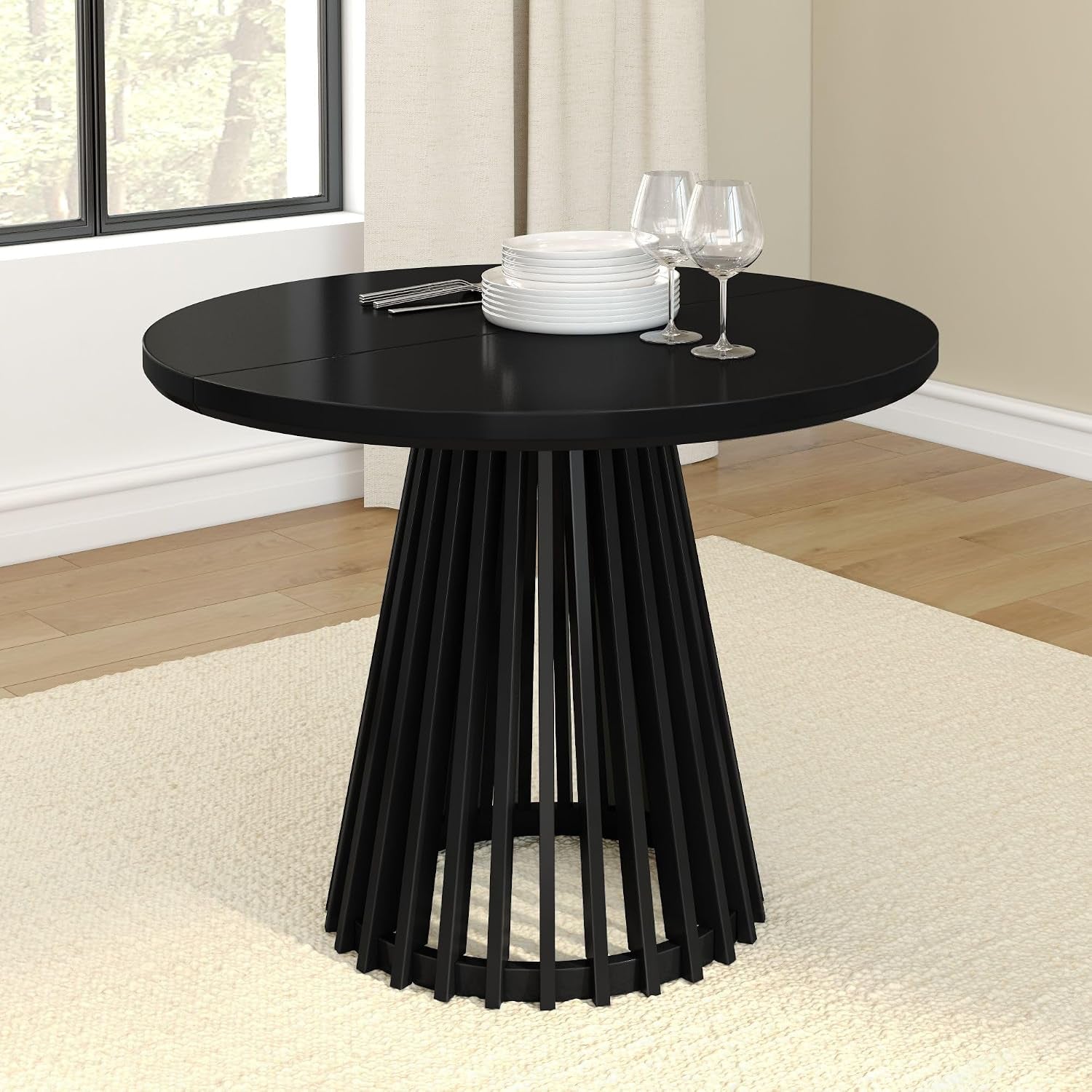 Round black dining table viewed slightly from the side, showing the open slatted pedestal base