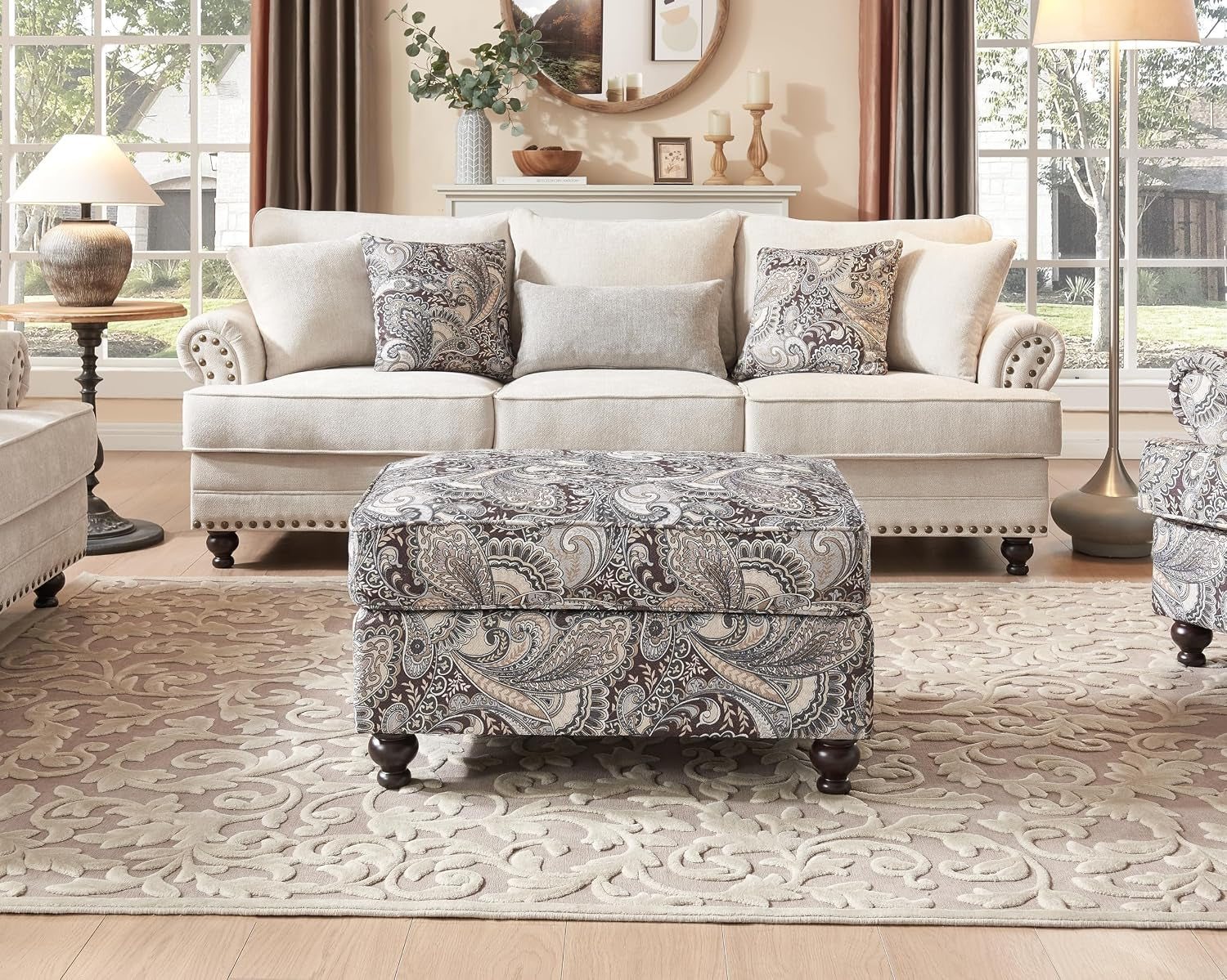 Front view of a three-seat beige sofa with paisley-patterned ottoman centered on a textured area rug.