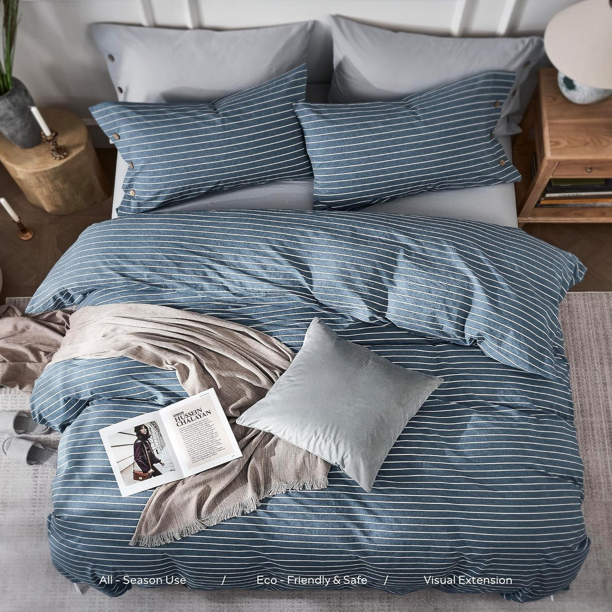 Overhead view of bed with blue striped duvet, pillows, a gray cushion and an open magazine on top.