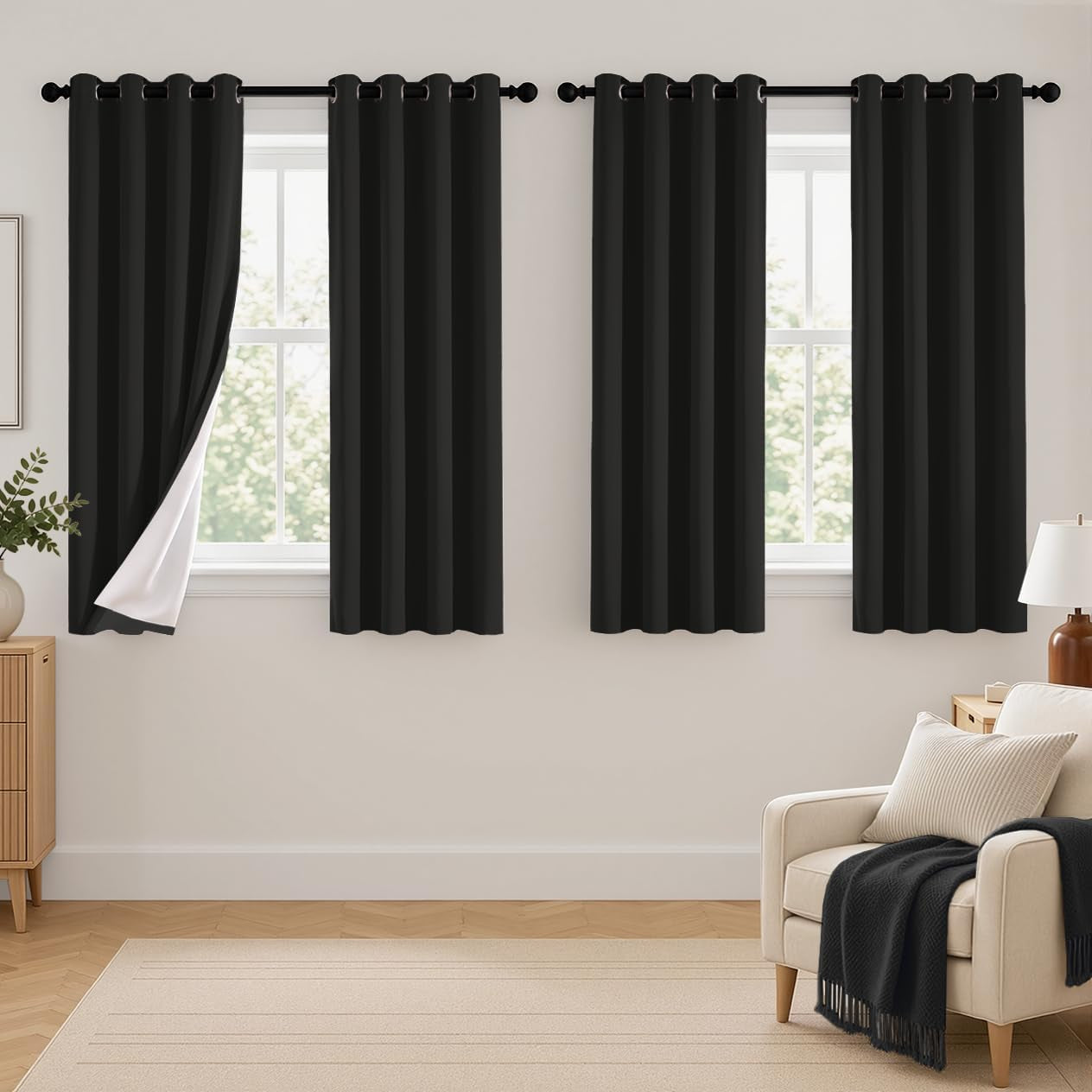 Three narrow black curtain panels hung in a row, leftmost panel pulled to reveal white backing at the edge.