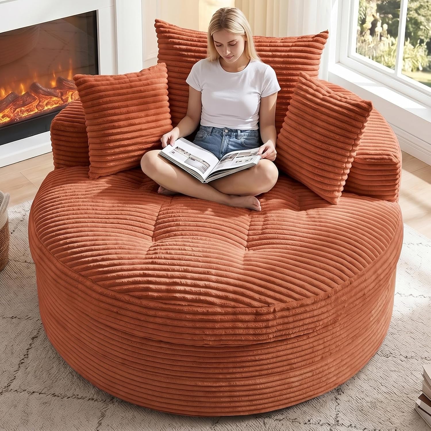 Large round corduroy floor chaise in warm terracotta with ribbed cushions, woman sitting cross‑legged reading