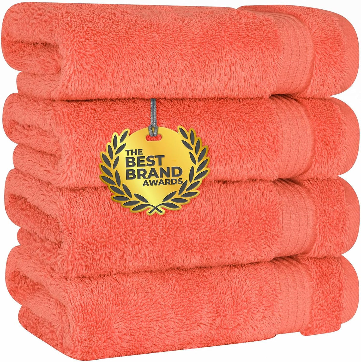 Four coral-colored folded towels stacked with a gold award tag over the center