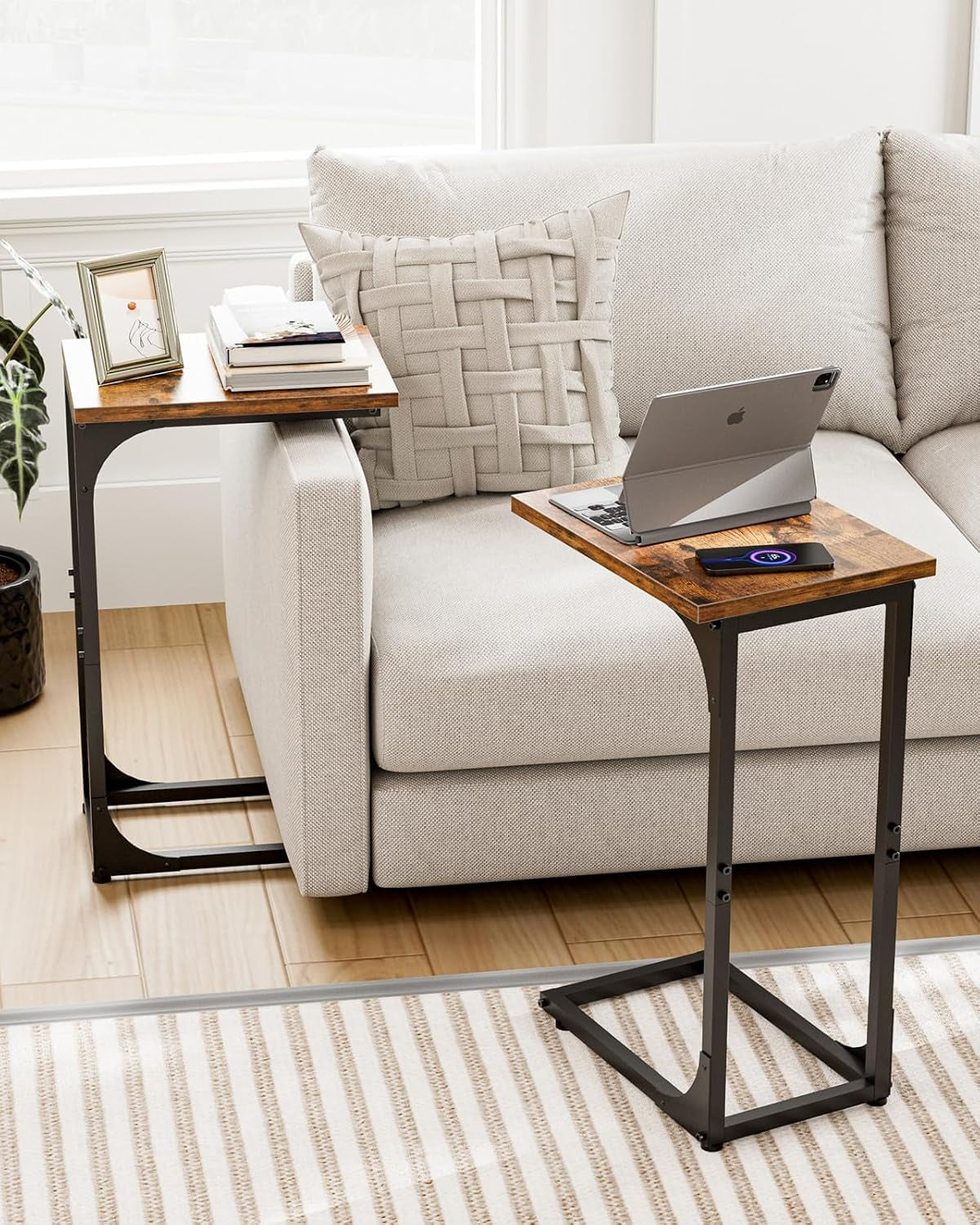 Two C-shaped end tables in a living room scene, one beside sofa and one in front with tablet on top