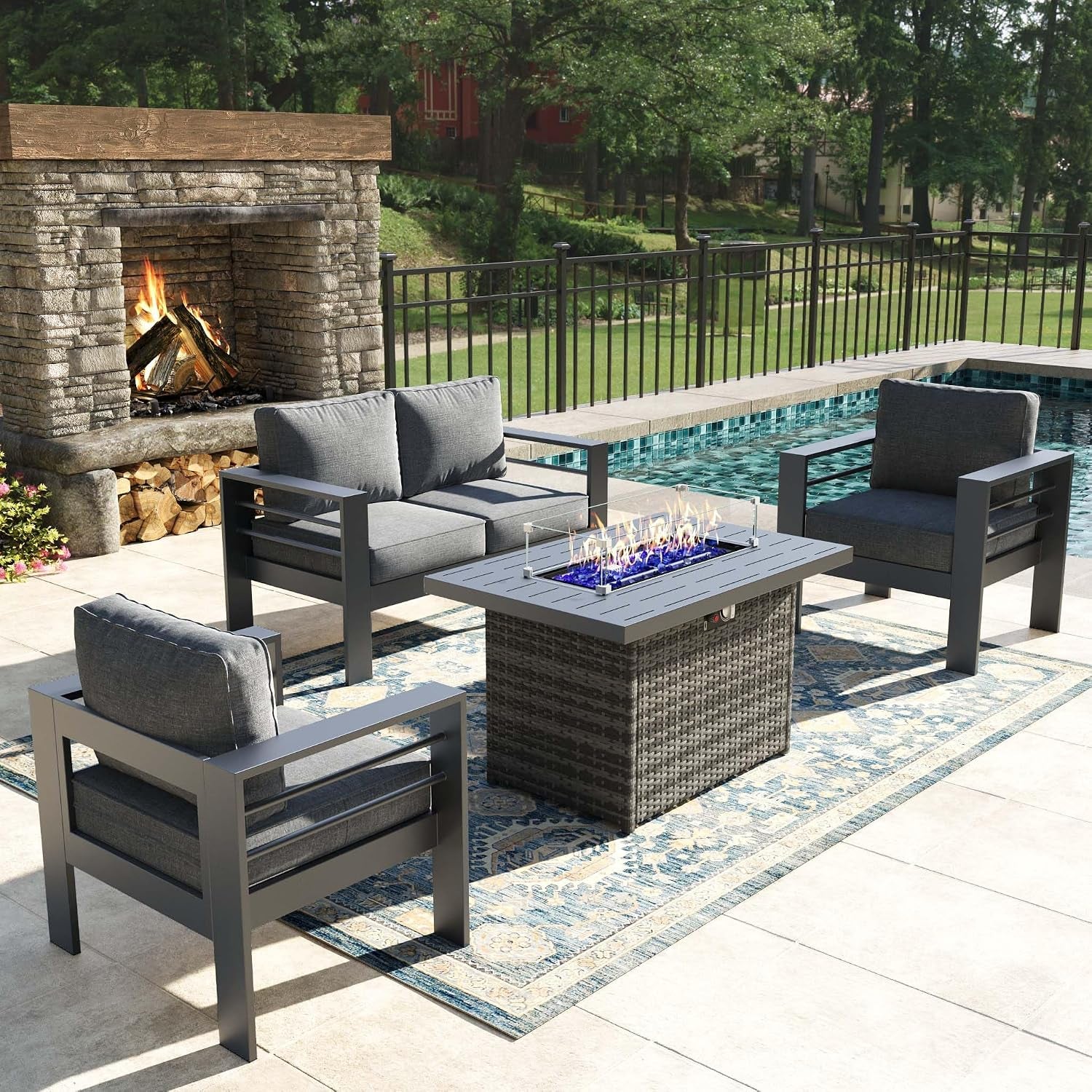 Same patio arrangement with a rectangular fire pit table burning blue flames at the center on a patterned rug.