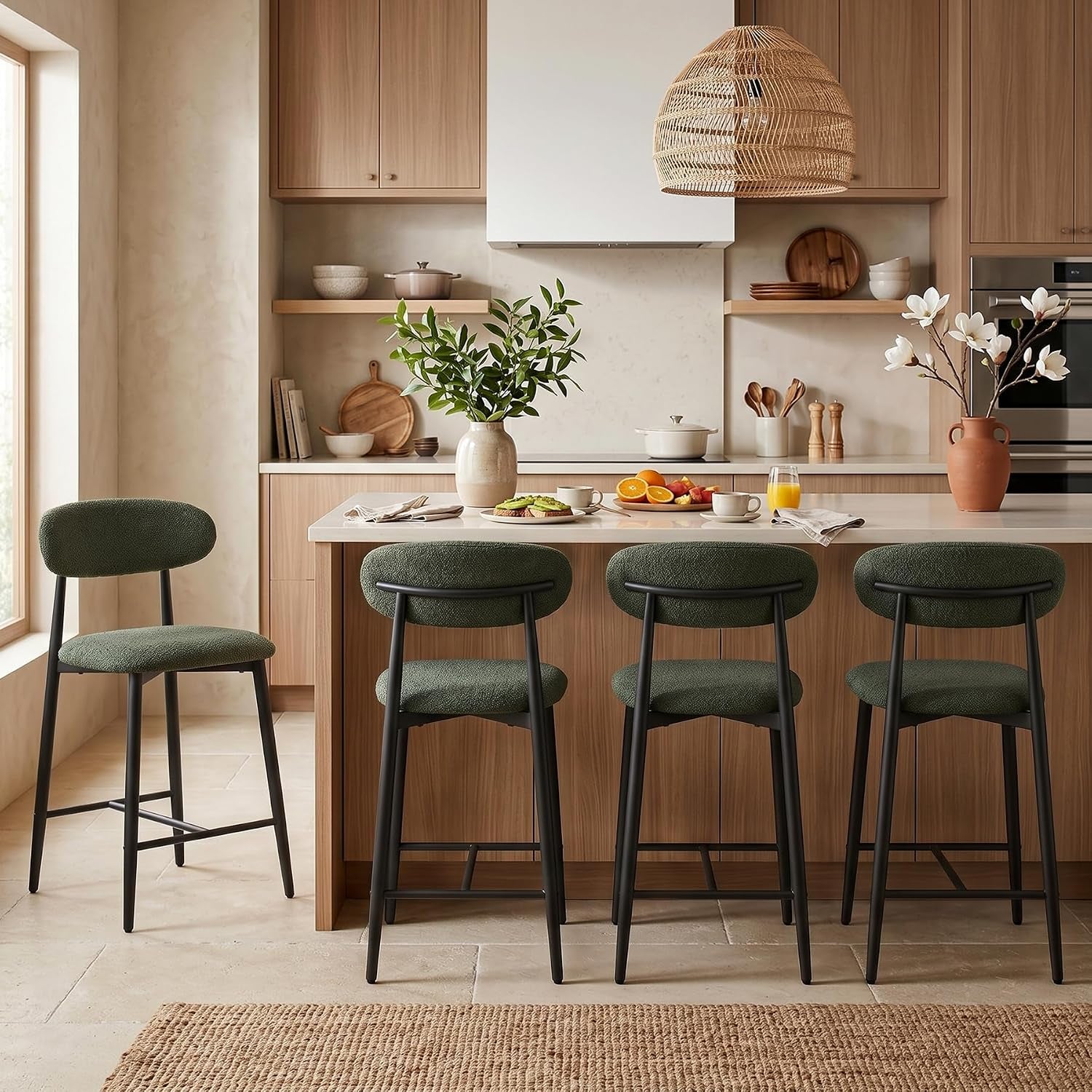 Four green upholstered counter stools with black metal legs tucked under a wooden island, one stool pulled out.