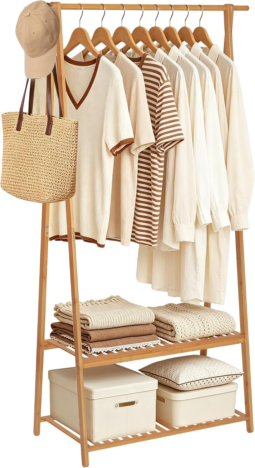 Freestanding light-wood garment rack with hanging rod, two slatted shelves, clothes and storage boxes.