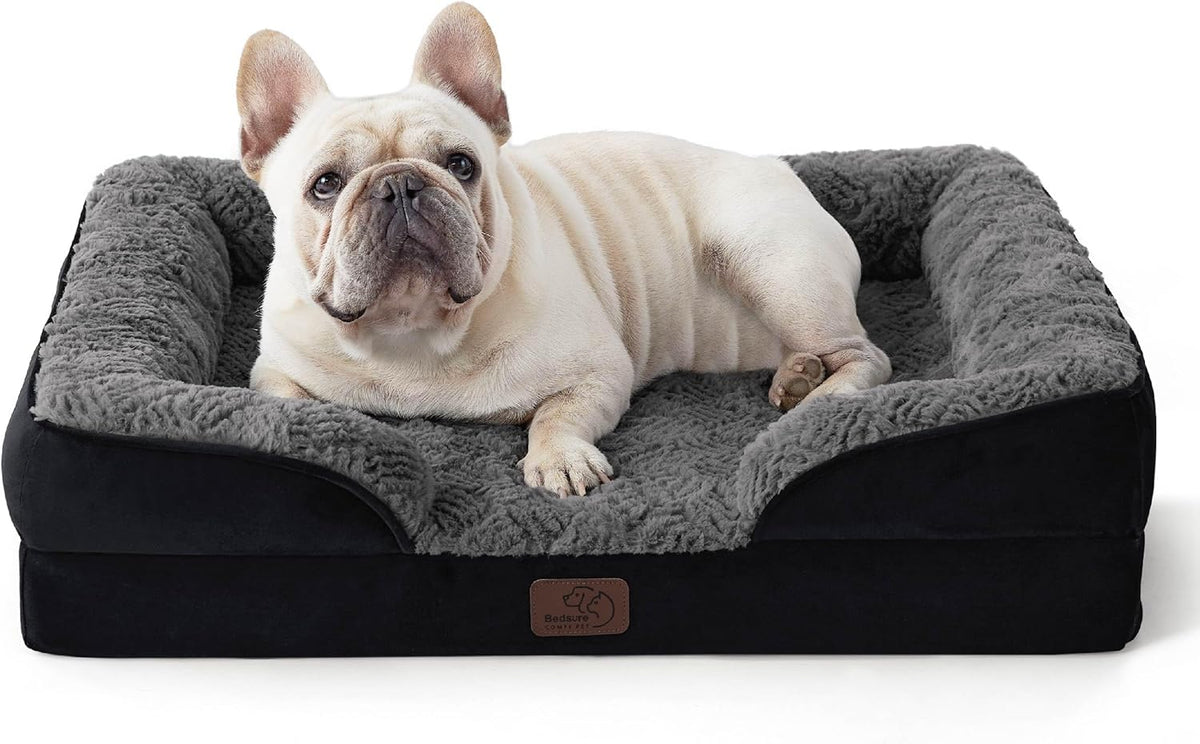 Cream-colored French bulldog lounging in a rectangular black dog bed with fluffy gray interior