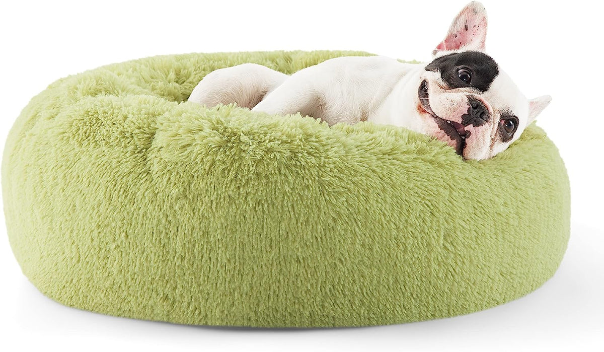 Green round faux-fur donut pet bed with raised rim and a small white dog curled inside