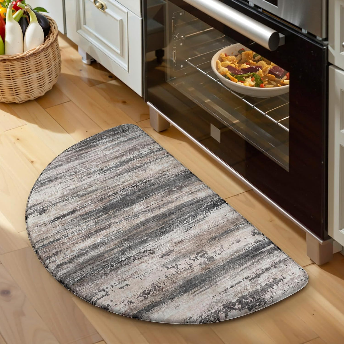 Close-up of a textured half-round gray mat placed in front of a stainless oven on wood floor.