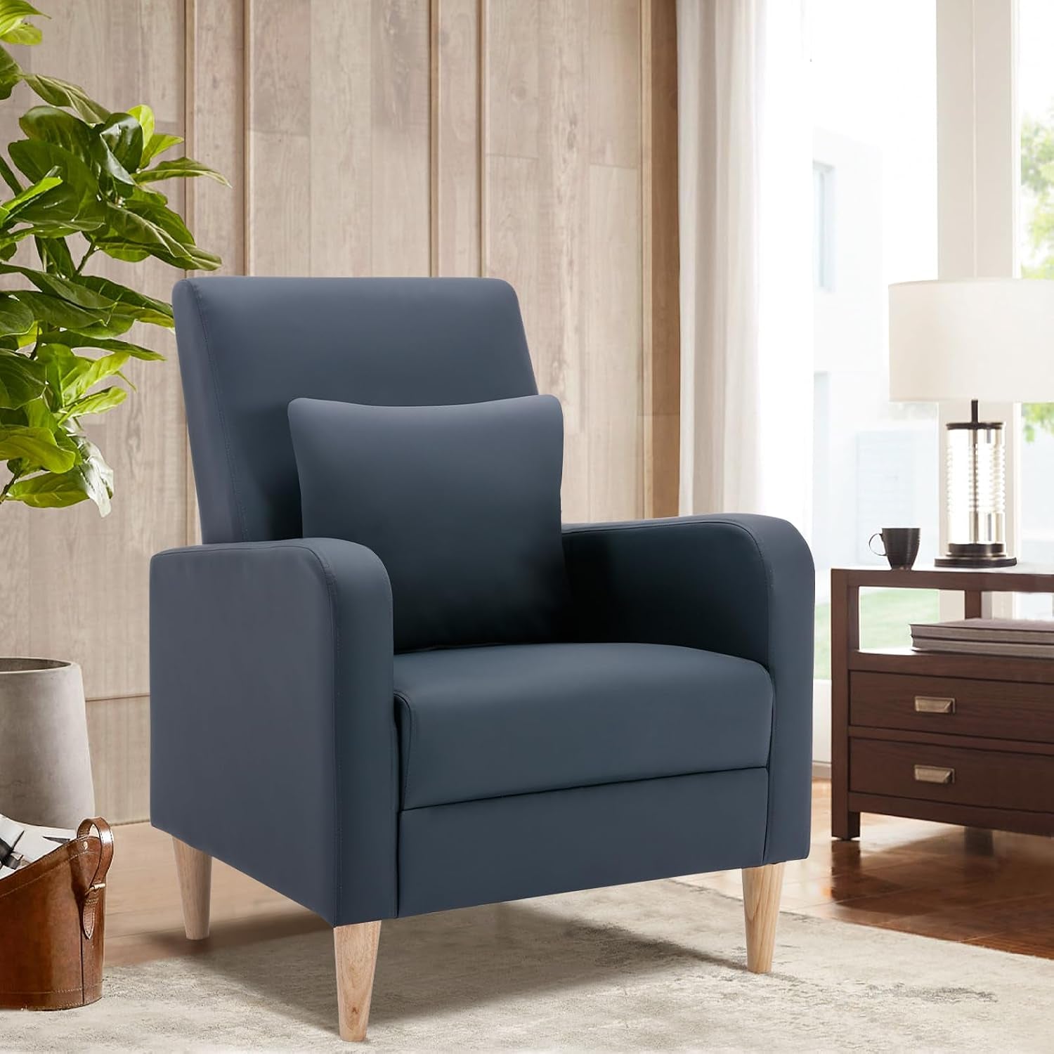 Single navy high-back accent chair with matching pillow beside a wooden side table and lamp.