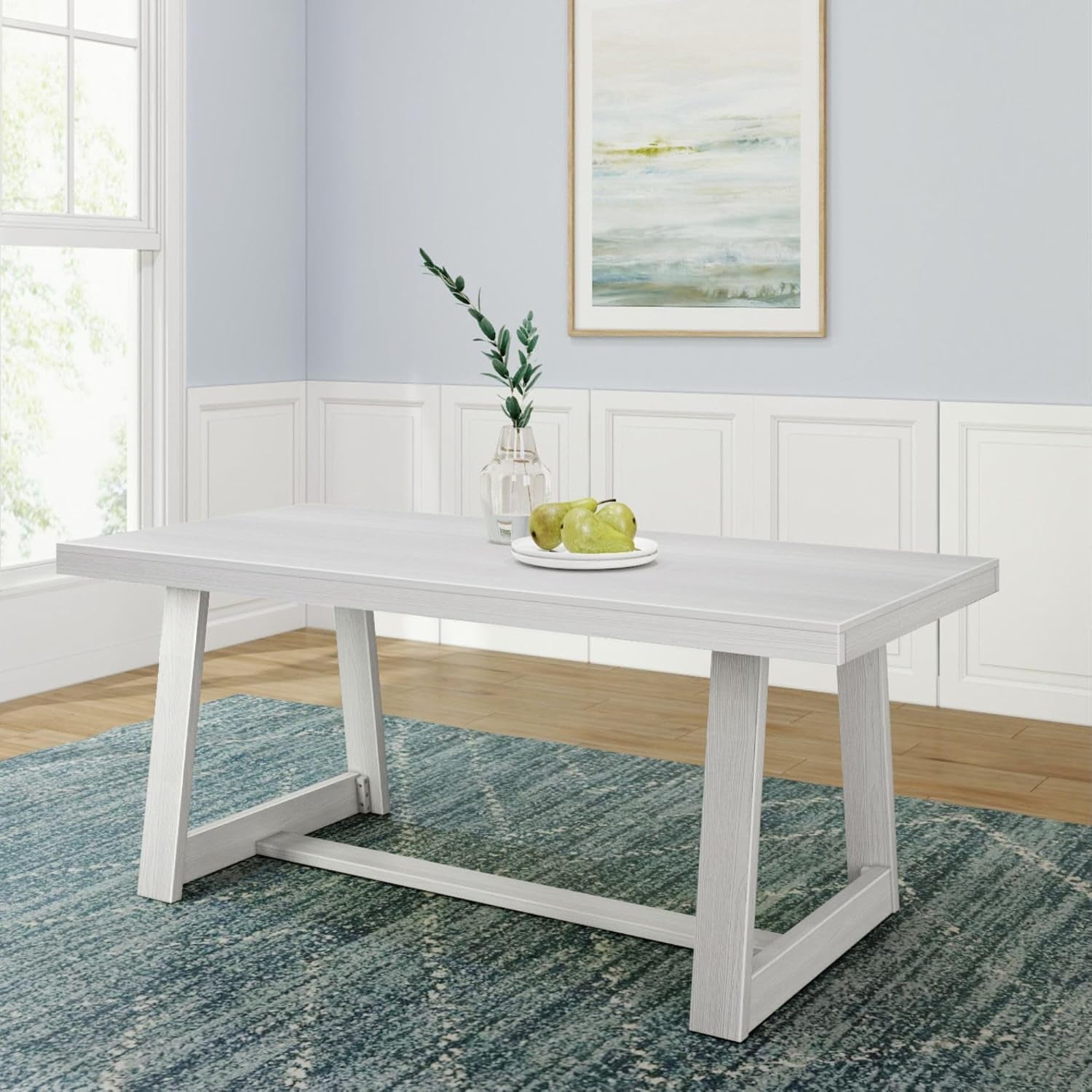 White-finished dining table on a blue rug with a plate of pears and a vase.