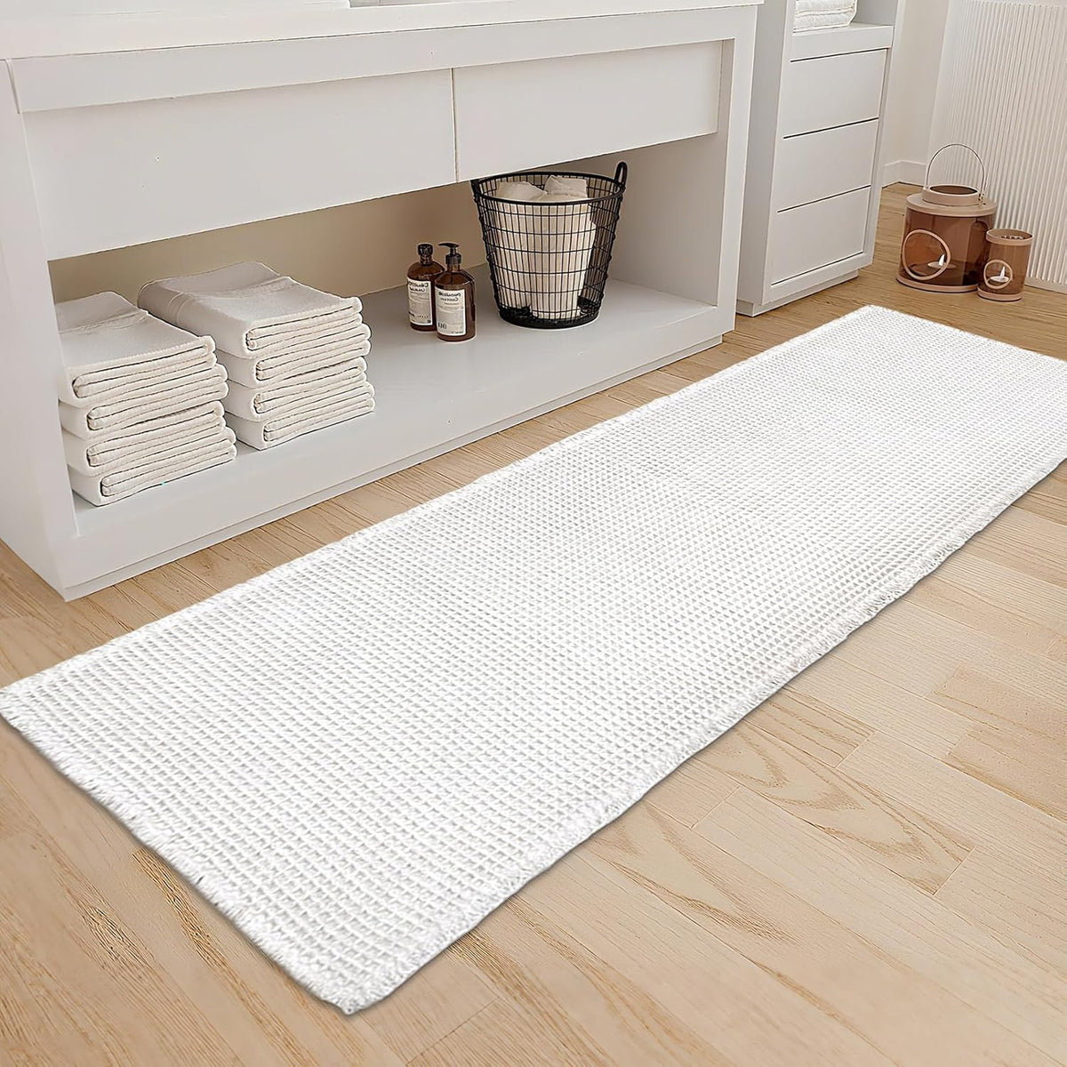 Long white waffle-texture runner placed on a light wood bathroom floor in front of storage shelves