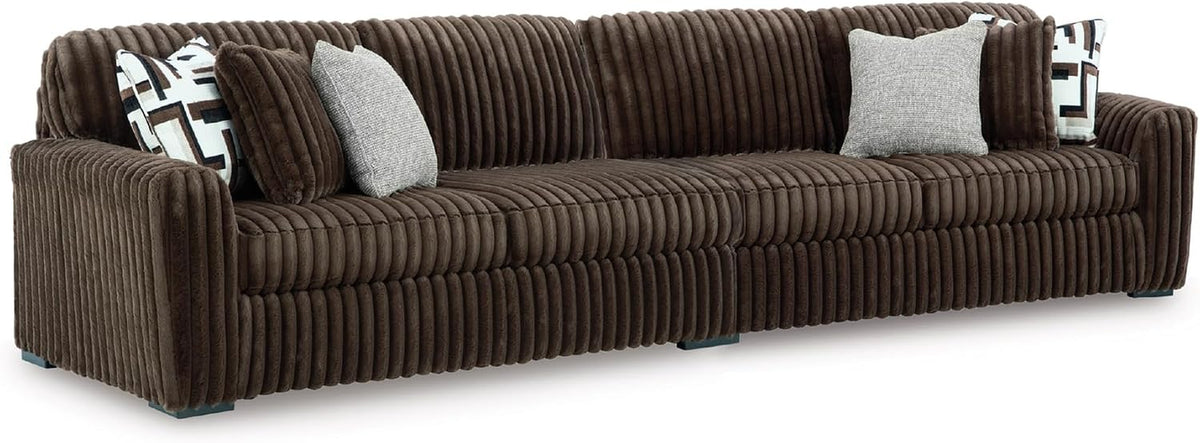 Long front view of a chocolate-brown oversized sofa with deep vertical channels and several throw pillows.