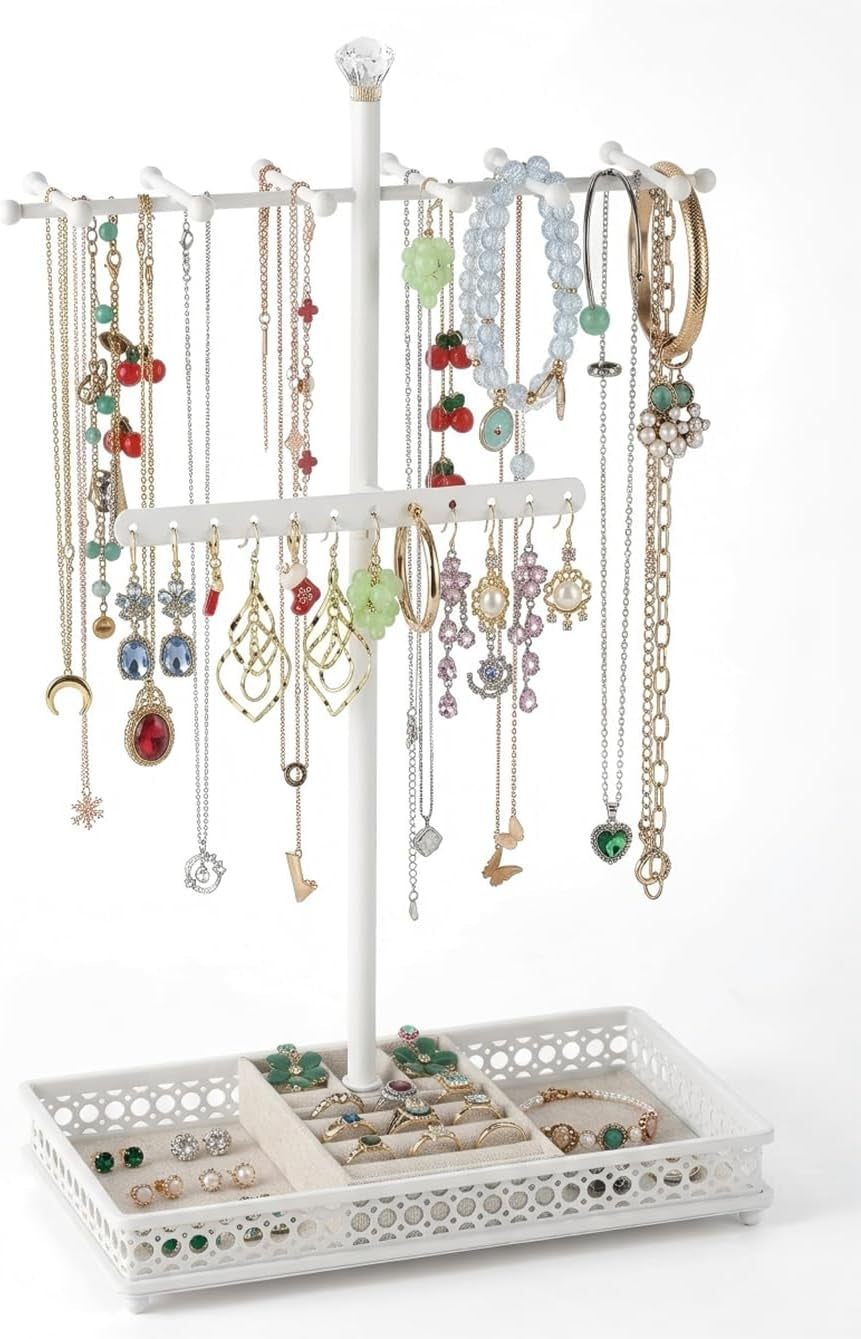 Close three-quarter shot of a white necklace stand with bracelets draped over the top and rings in the tray