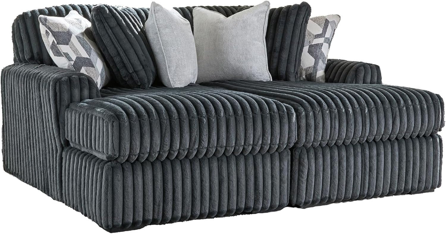 Angled close view of an oversized ribbed chaise seat with three textured throw pillows.