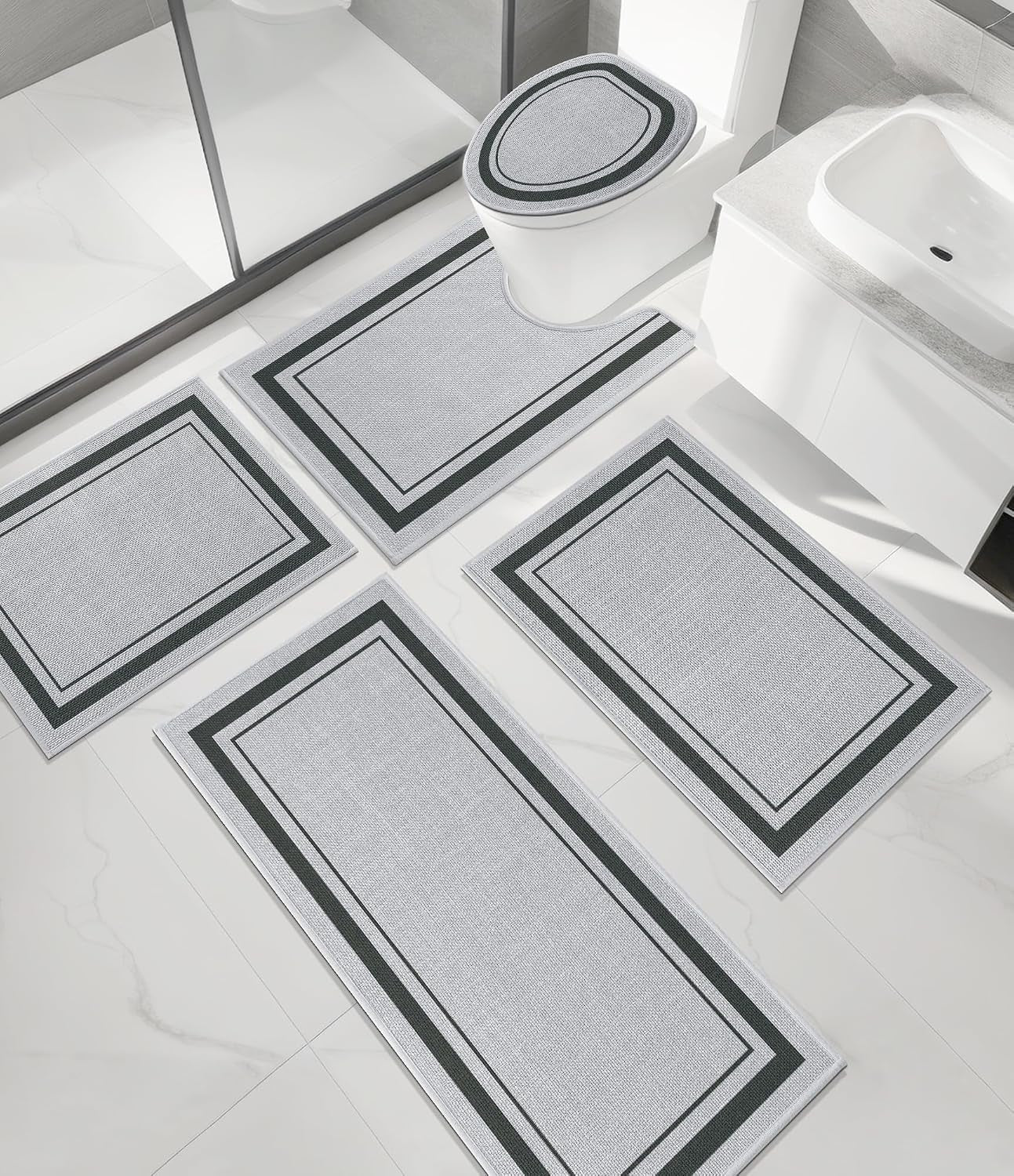 Four matching beige rugs including U-shaped toilet mat arranged on white bathroom tile