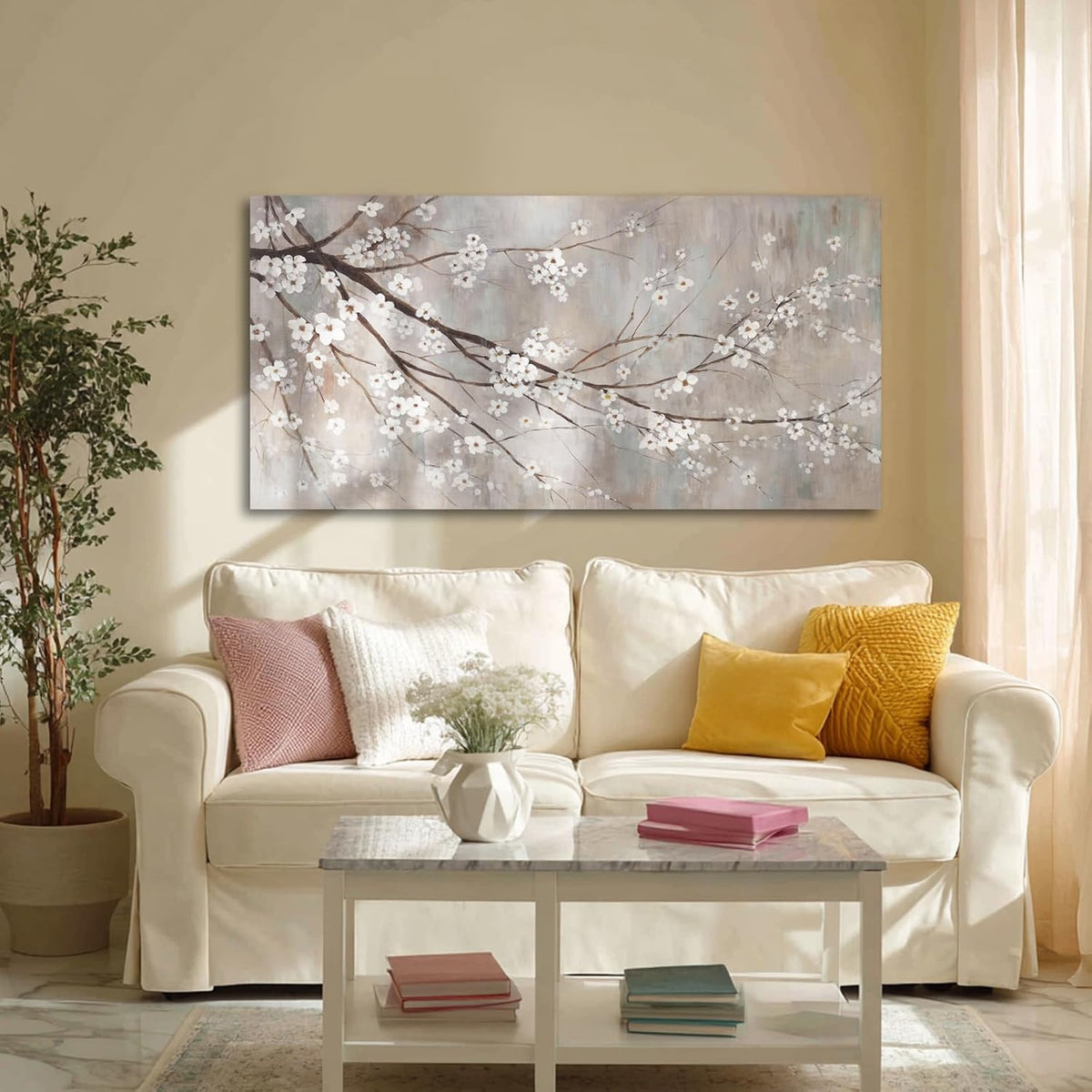 Front view of a plum-blossom canvas above a cream sofa, potted plant at left, sheer curtains at right and a coffee table