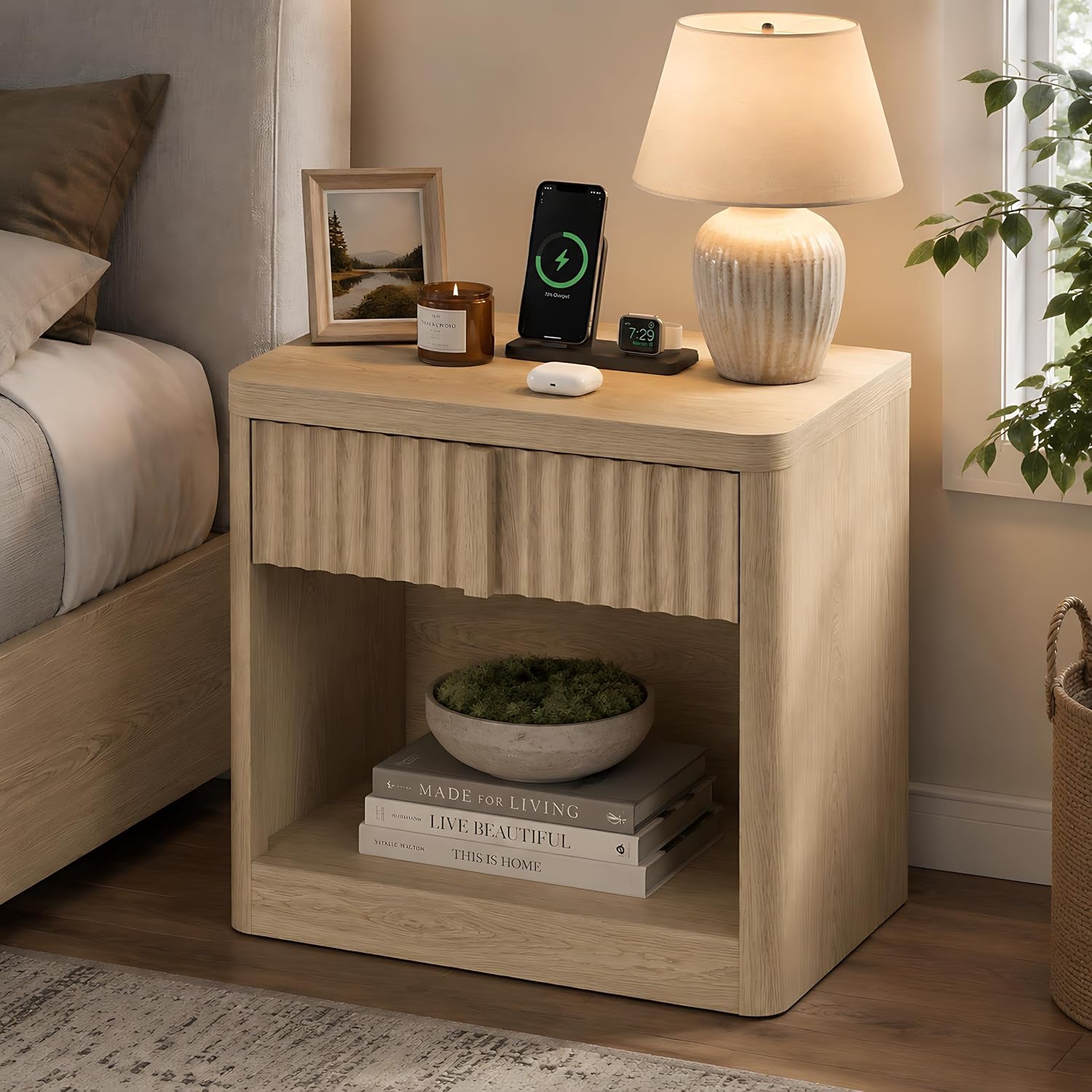 Light wood fluted nightstand beside a bed with lamp, phone, and open shelf with books and bowl