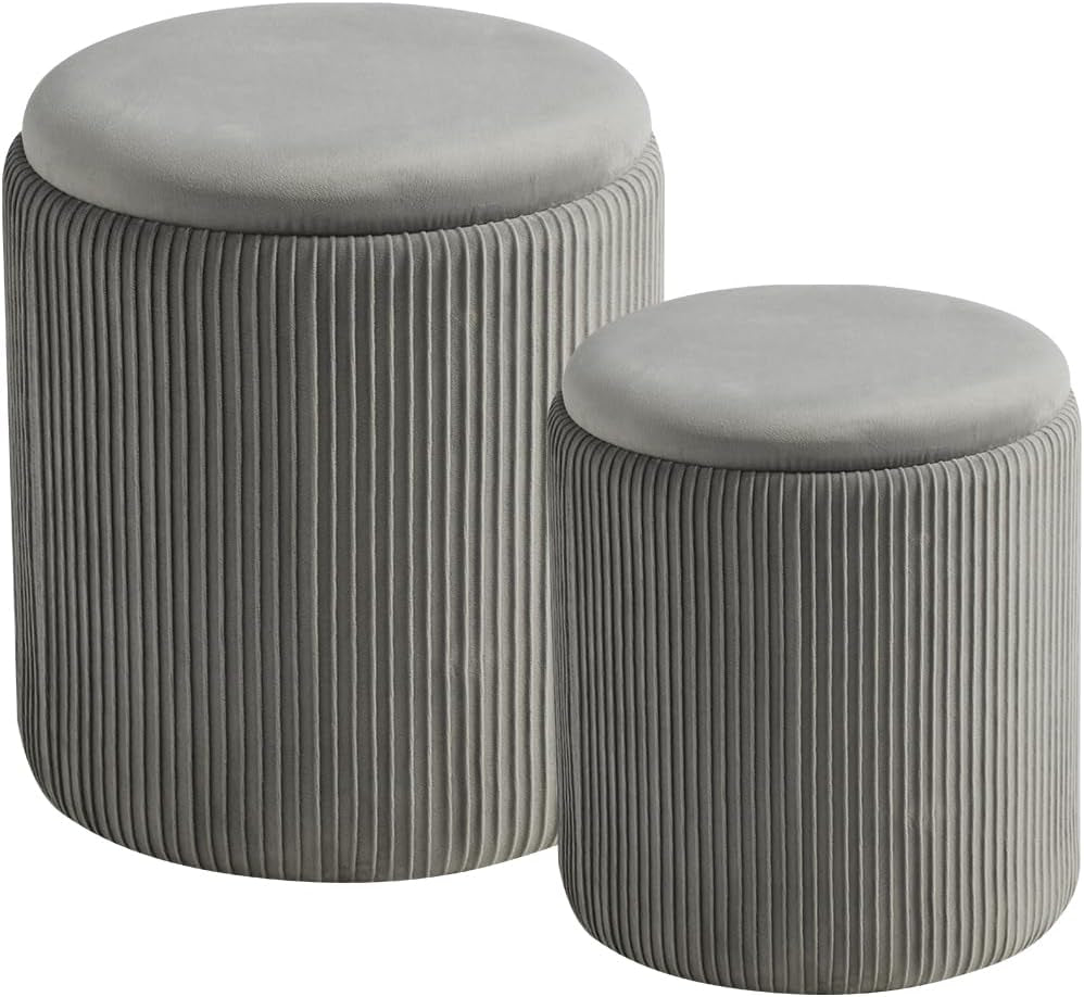 Two round light-gray velvet ottomans with vertical pleated sides and lids on against a white background.