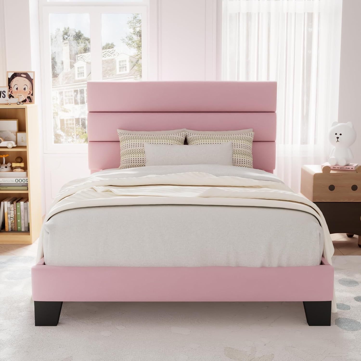 Front children's room view of a pink upholstered bed with a tall three-panel headboard.