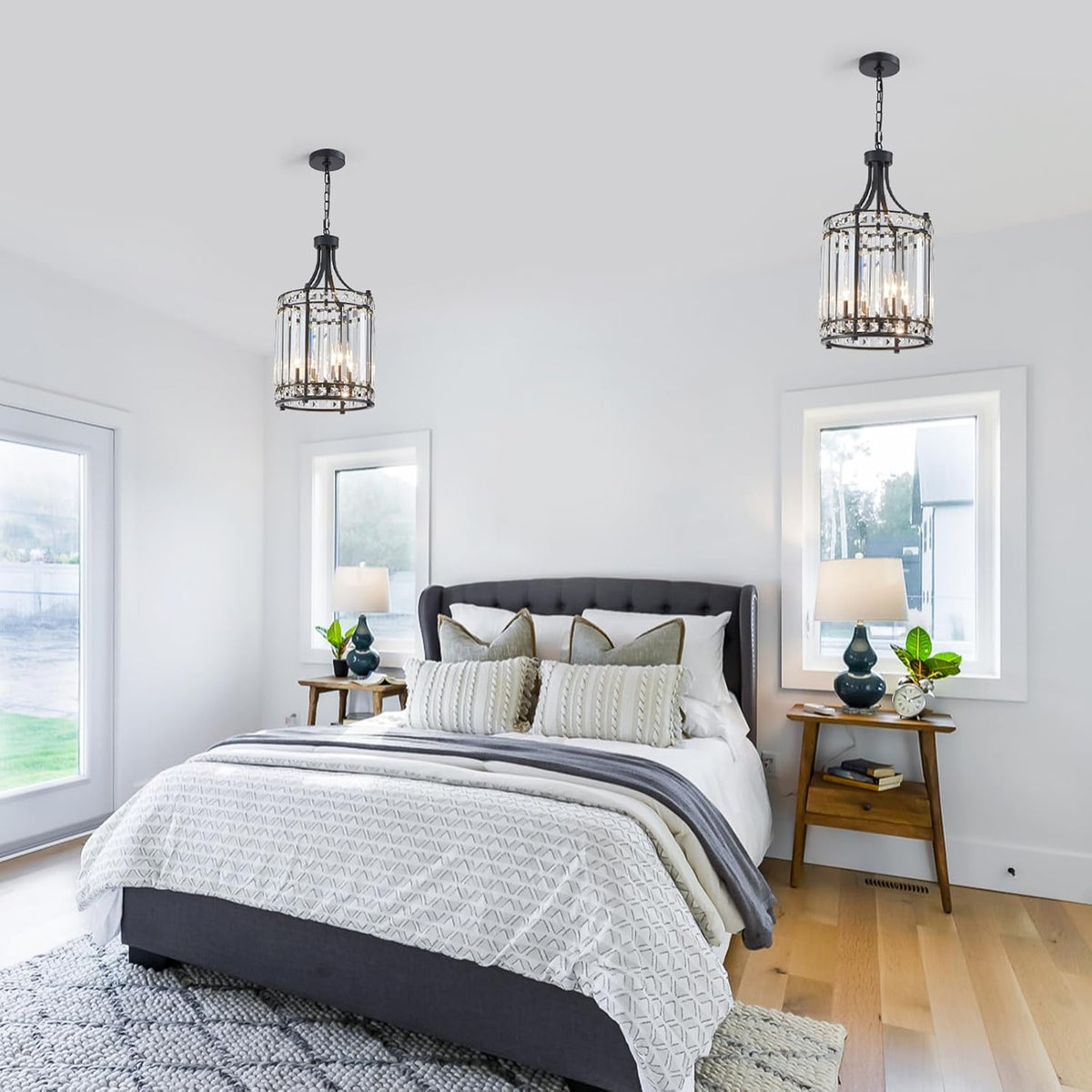 Two black crystal pendants suspended above a bed in a bright, minimal bedroom with bedside lamps.