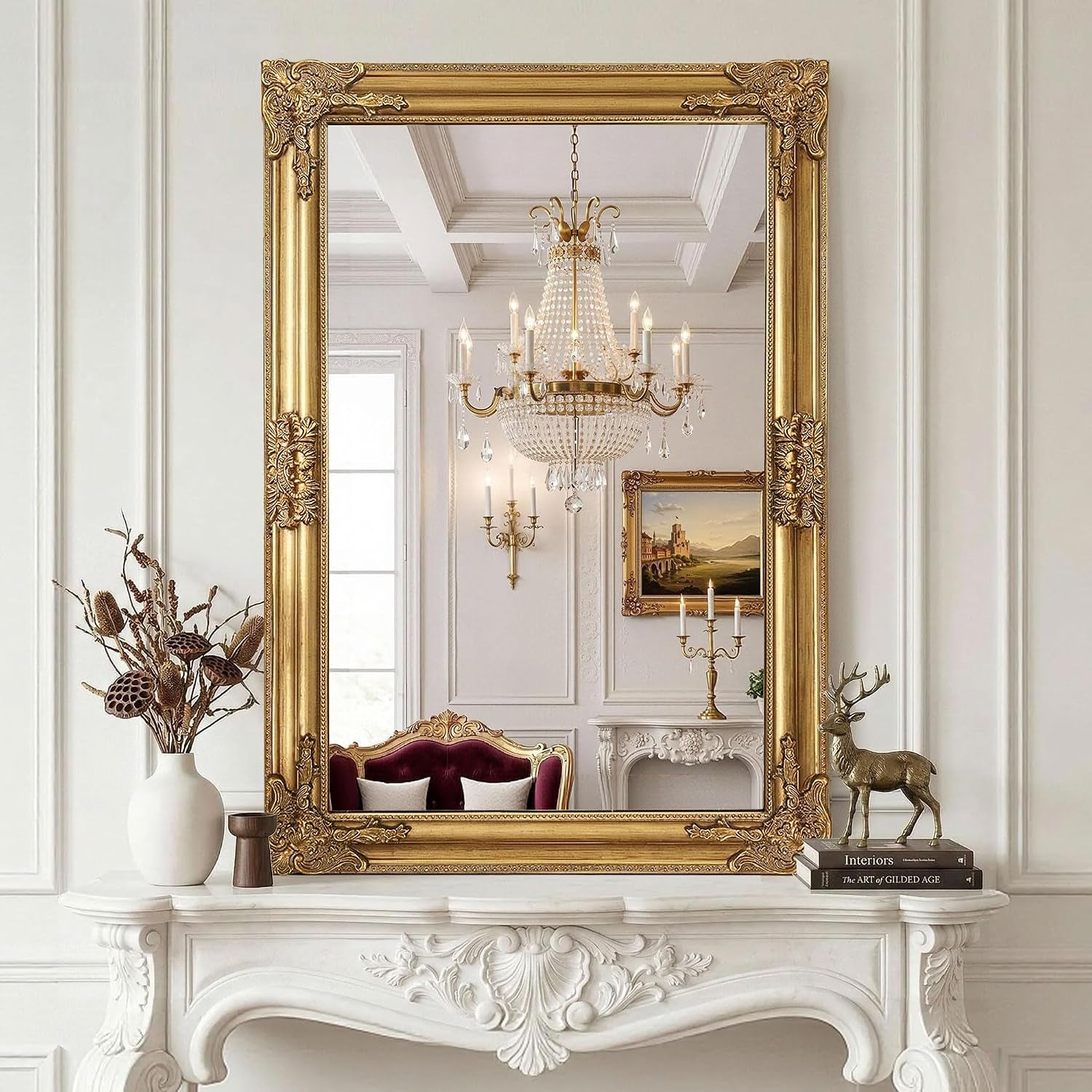 Full vertical view of an ornate gold wall mirror above a decorative white mantel with vase and deer figurine.