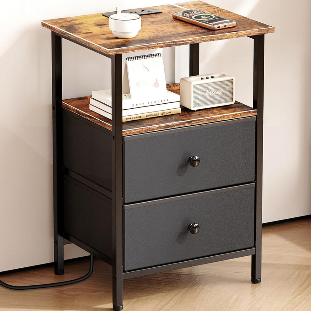 Front three-quarter view of a nightstand with wood top, open shelf and two dark fabric drawers in a black metal frame.