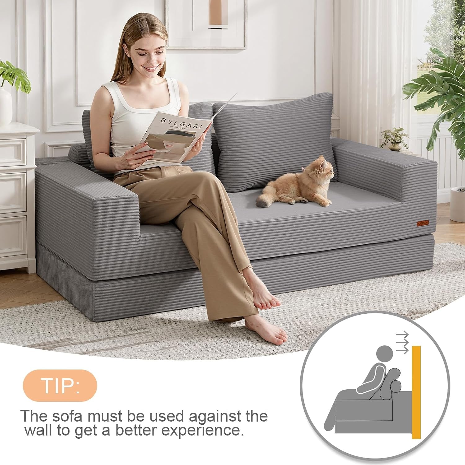 Woman seated on grey corded-fabric sofa with cat, angled living room scene showing armrests and cushions