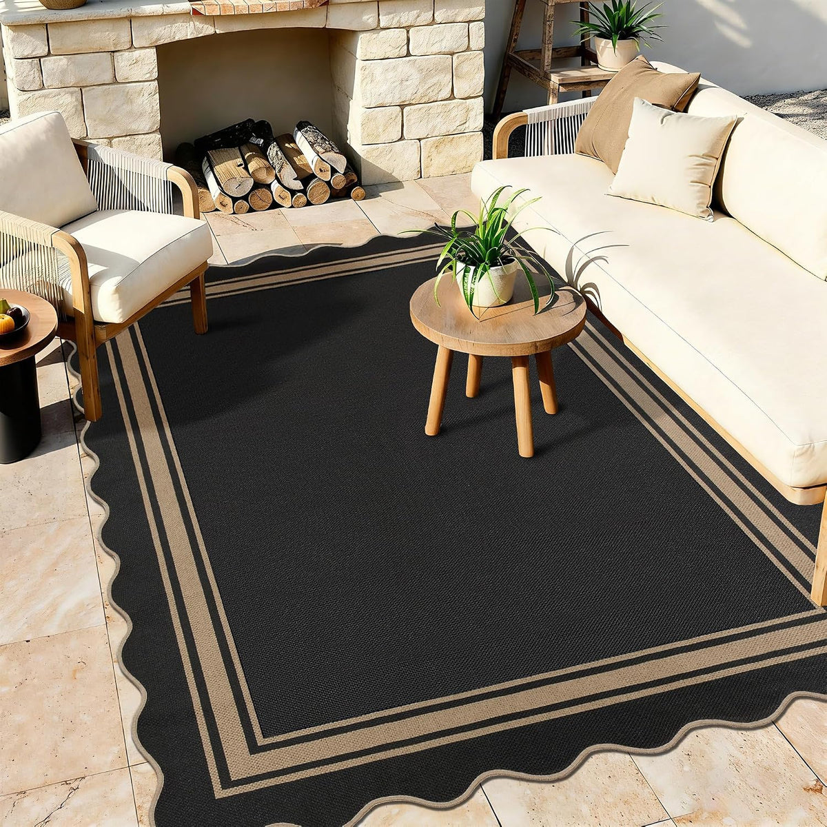 Outdoor patio scene with a scalloped black rug under a small round table and beige seating.