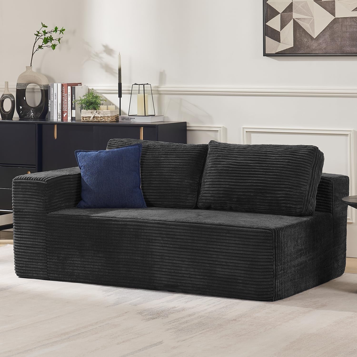 Black two-seat modular sofa with ribbed fabric and a blue accent pillow in a living room setting.