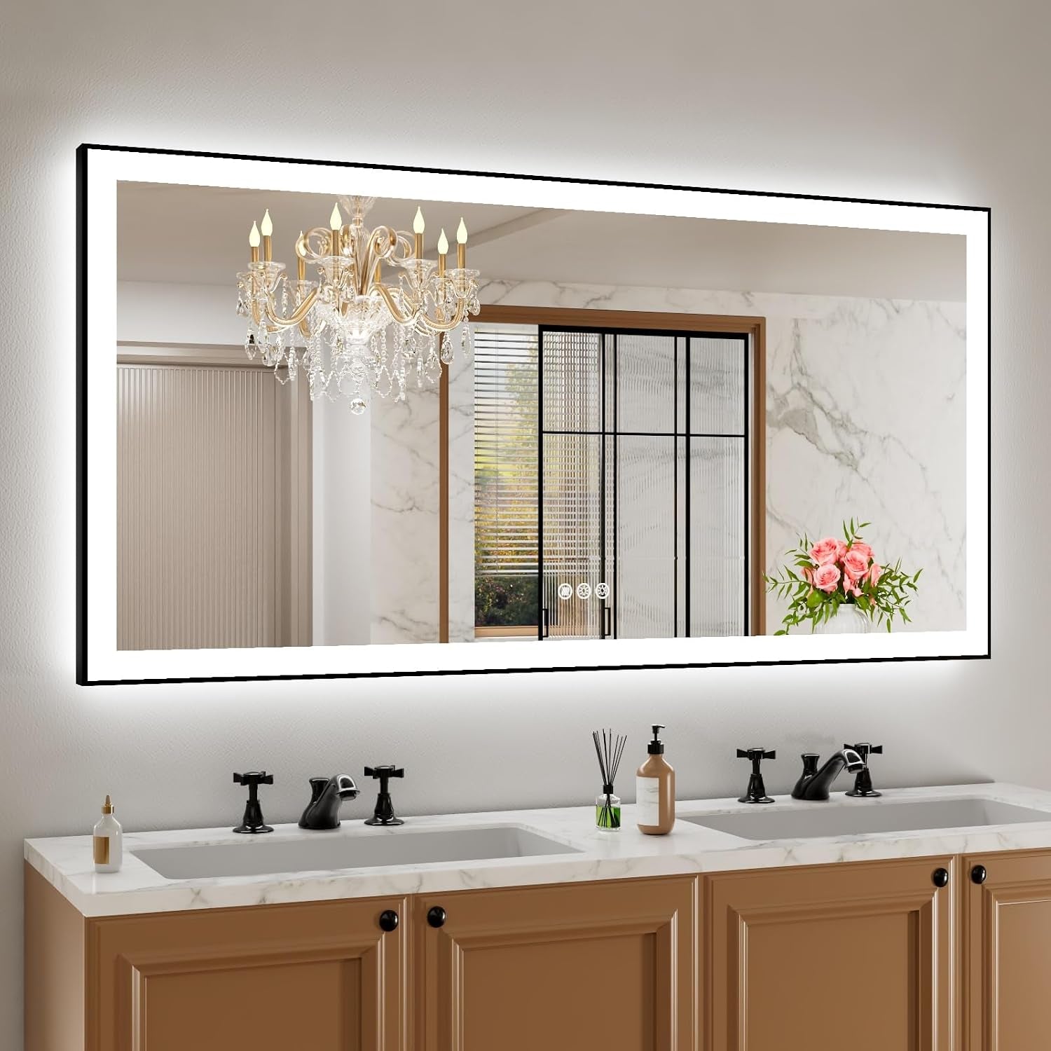 Large illuminated rectangular mirror above a double sink vanity reflecting chandelier and sliding door