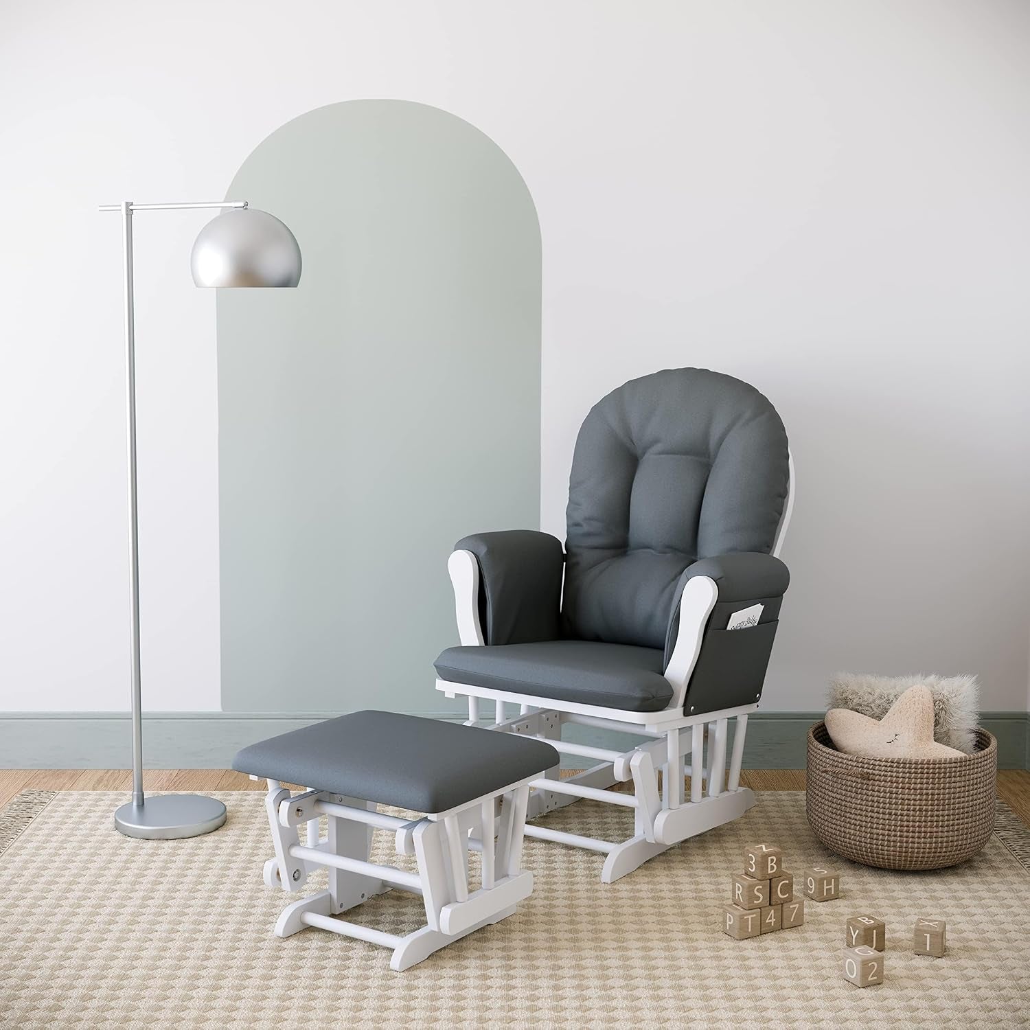 Gray-cushioned glider and ottoman staged on a patterned rug next to a floor lamp and a woven toy basket.