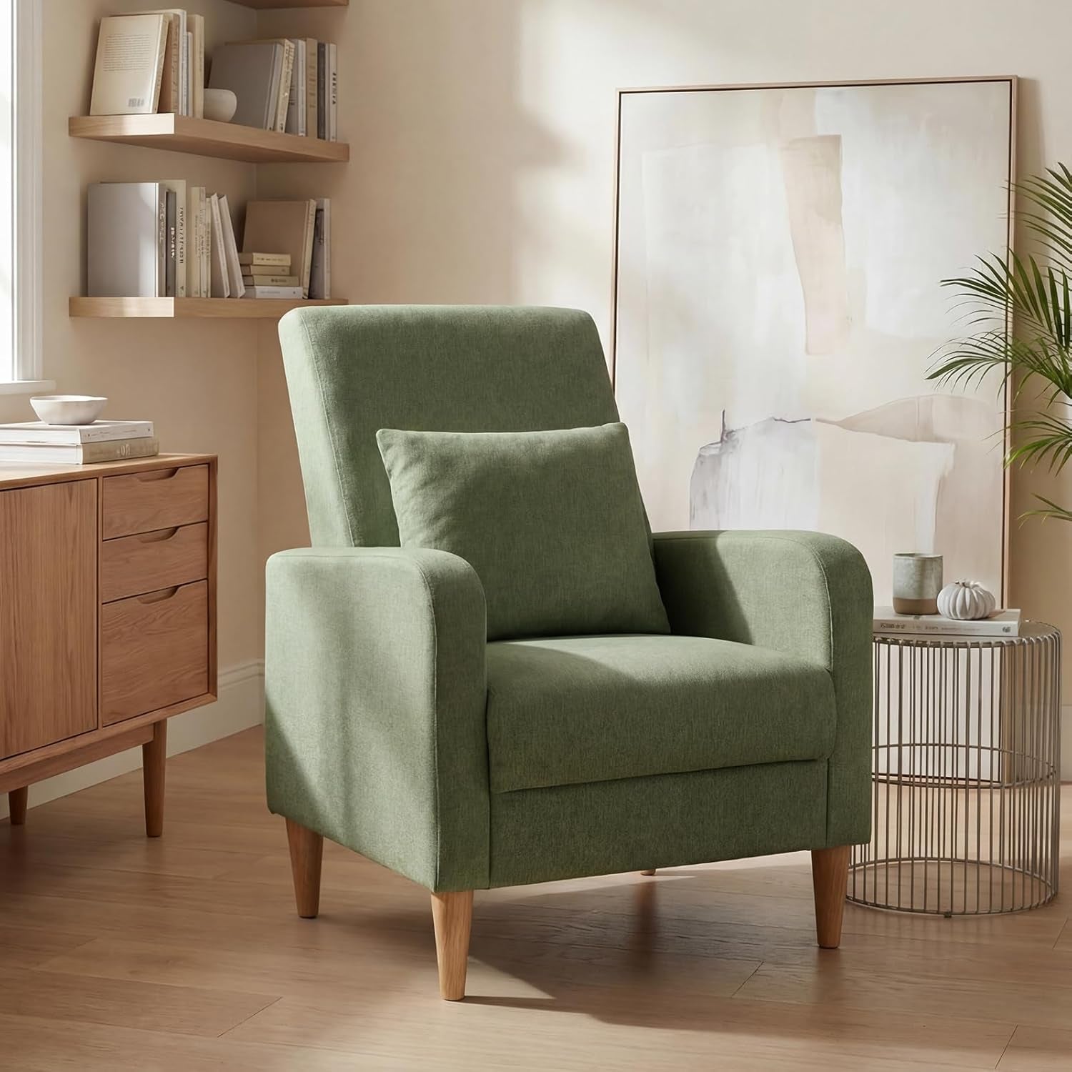 Single sage green fabric accent chair with cushion and tapered wood legs in a cozy corner