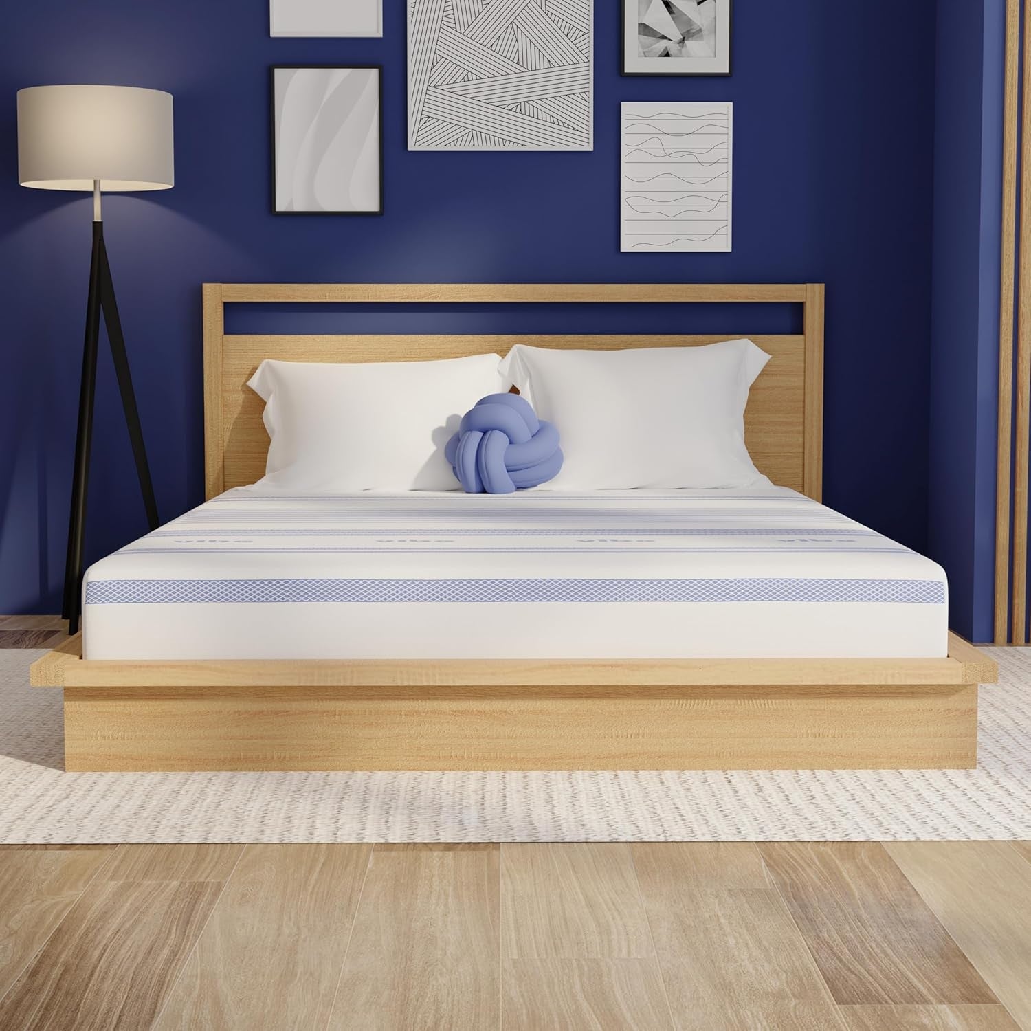 Centered front view of a mattress on a low wood bedframe in a blue-walled bedroom with pillows and a knot pillow.