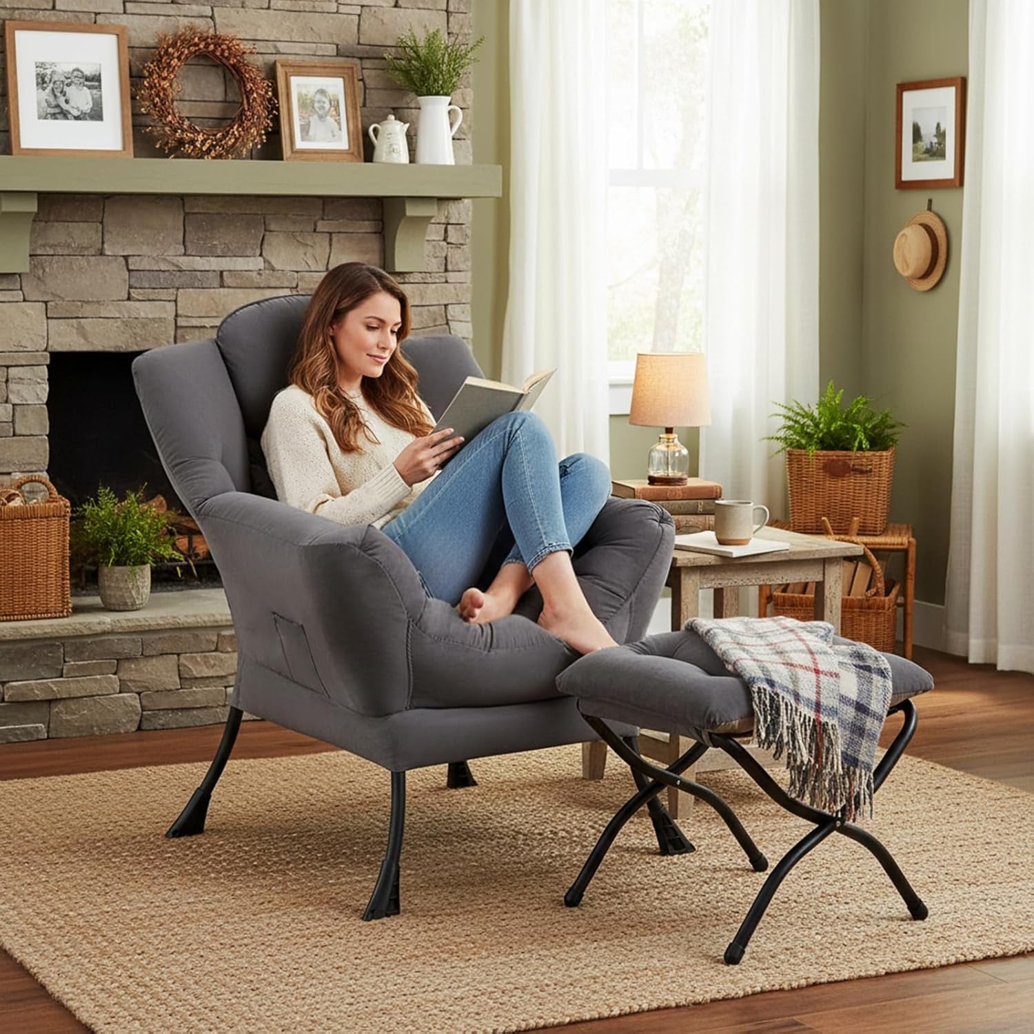 Woman reading in the gray lounge chair with ottoman next to a stone fireplace and side table