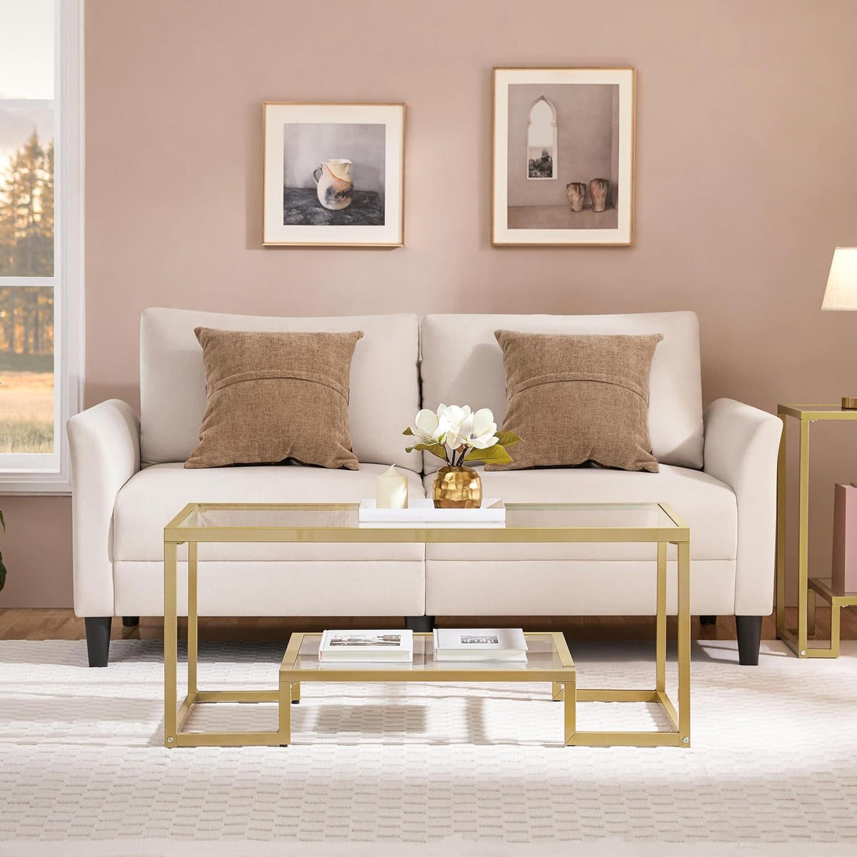 Gold metal-framed glass coffee table front view centered in living room with beige sofa and rug