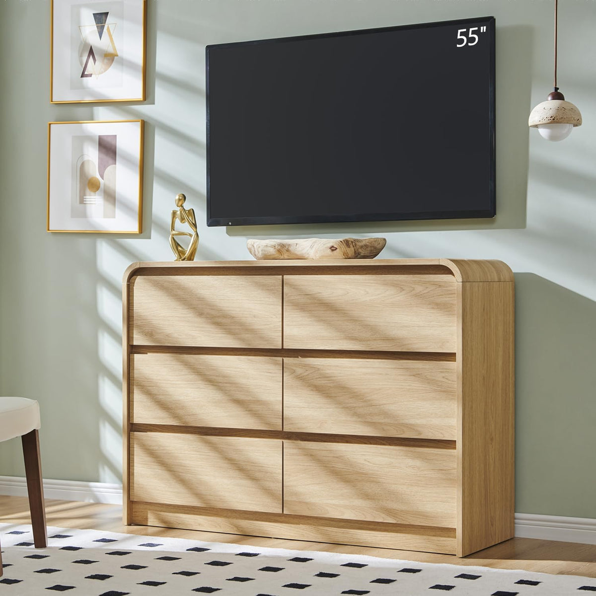 Light natural oak six-drawer dresser beneath a wall-mounted TV with sunlight and framed art nearby