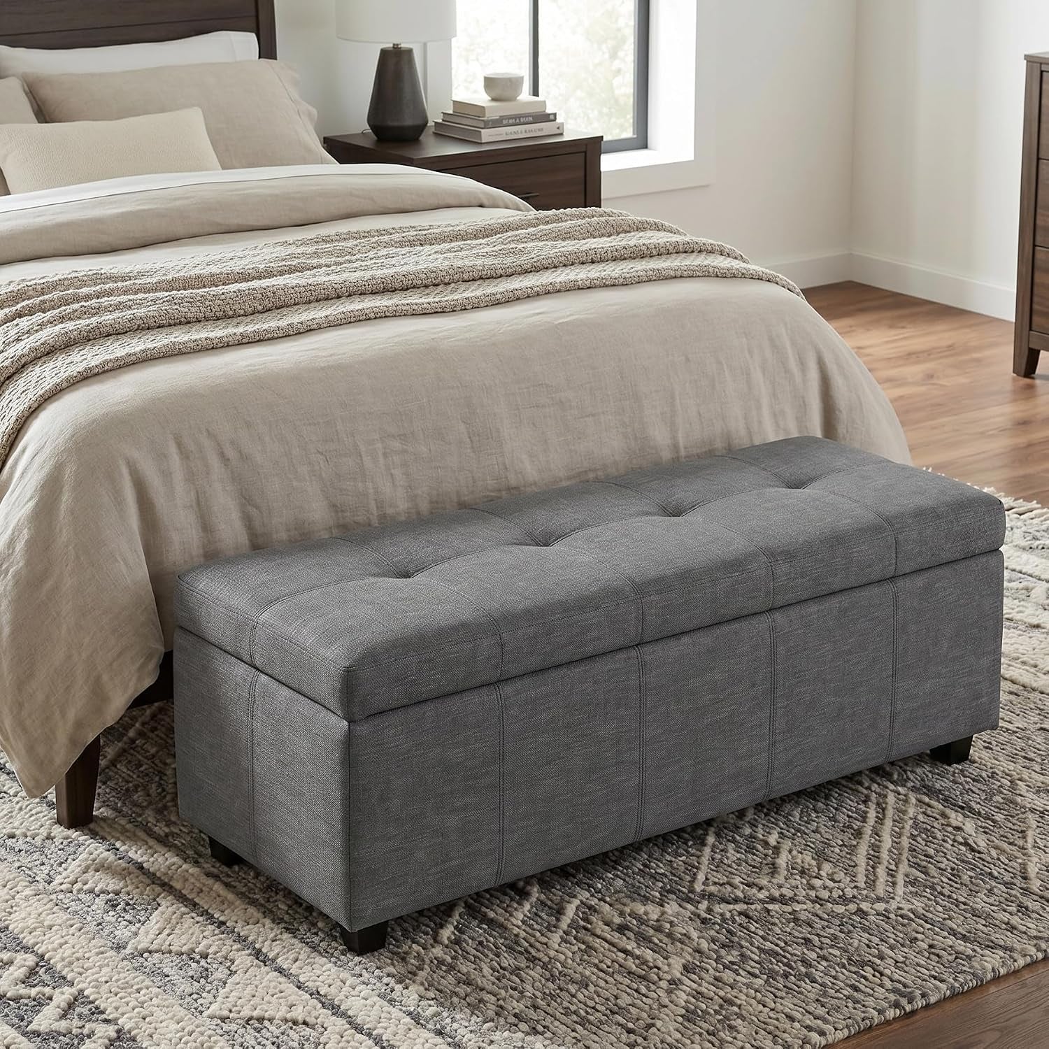 Slate grey storage ottoman bench with tufted-style lid placed at foot of bed in a styled bedroom
